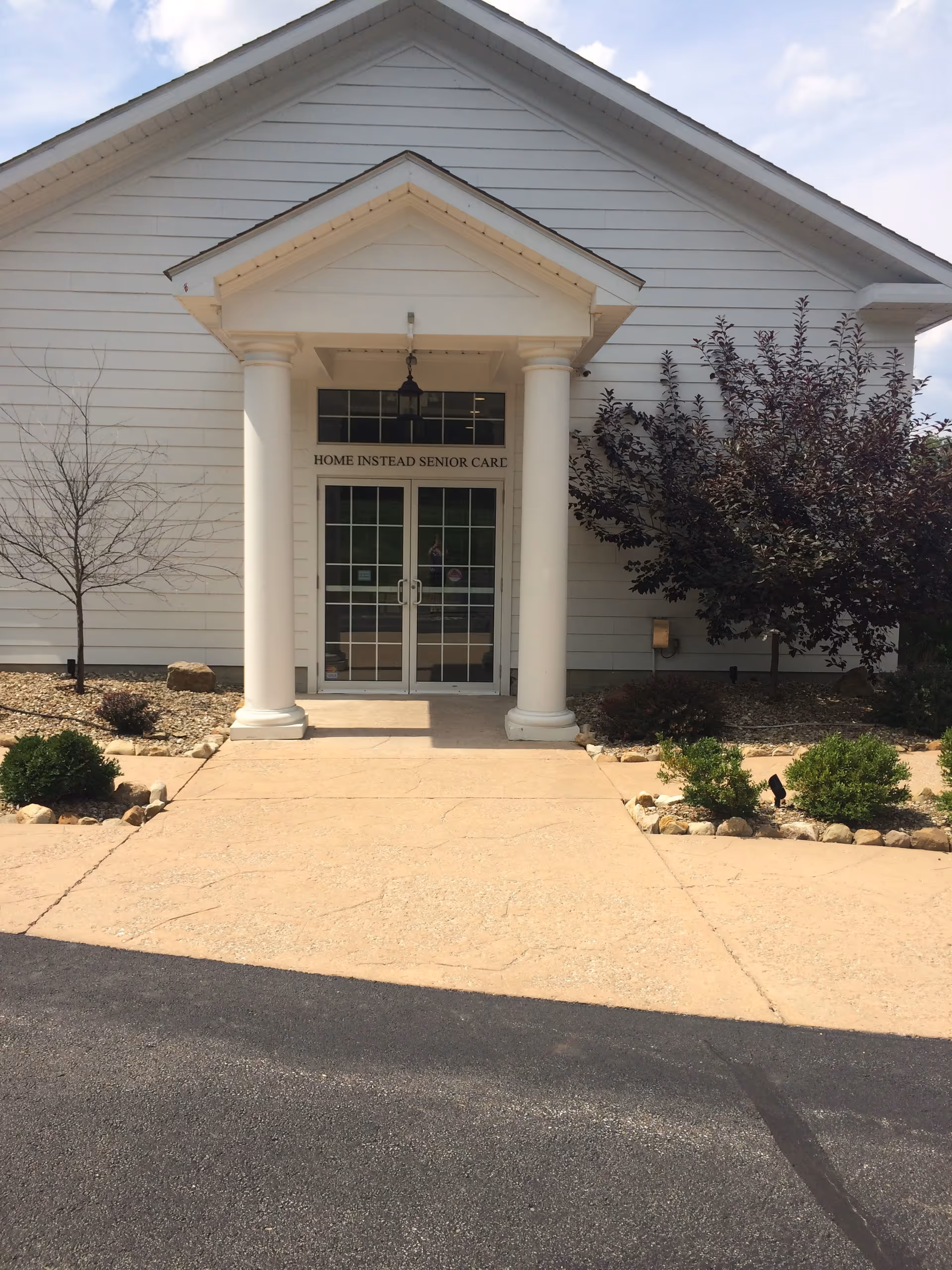 White building entrance with pillars and glass doors labeled Home Instead Senior Care.