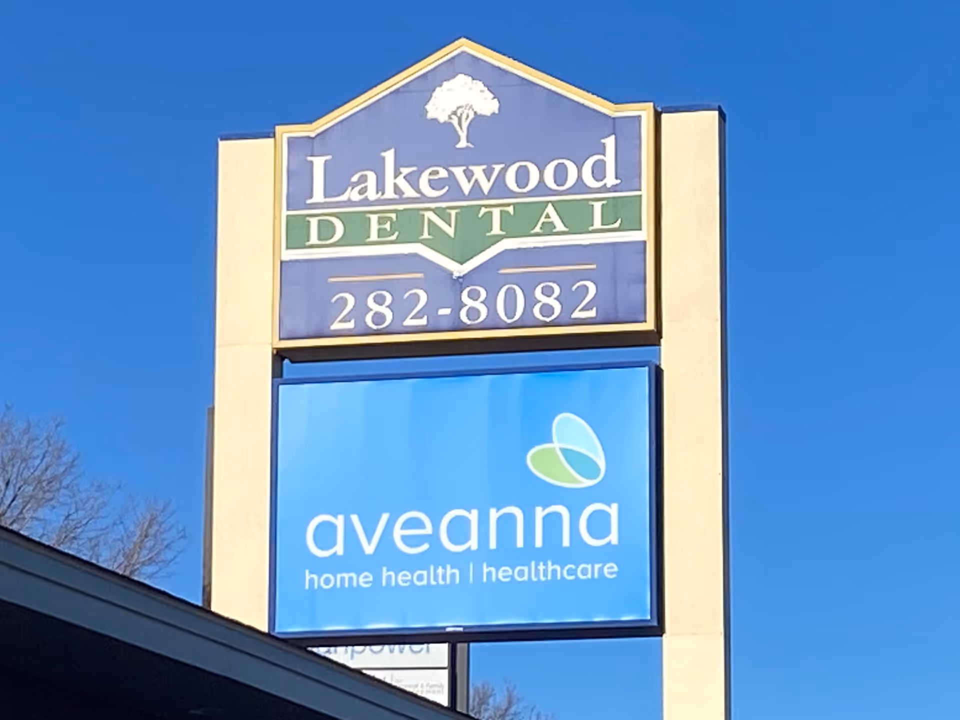 Tall outdoor sign featuring Lakewood Dental logo above Aveanna Home Health sign against blue sky.