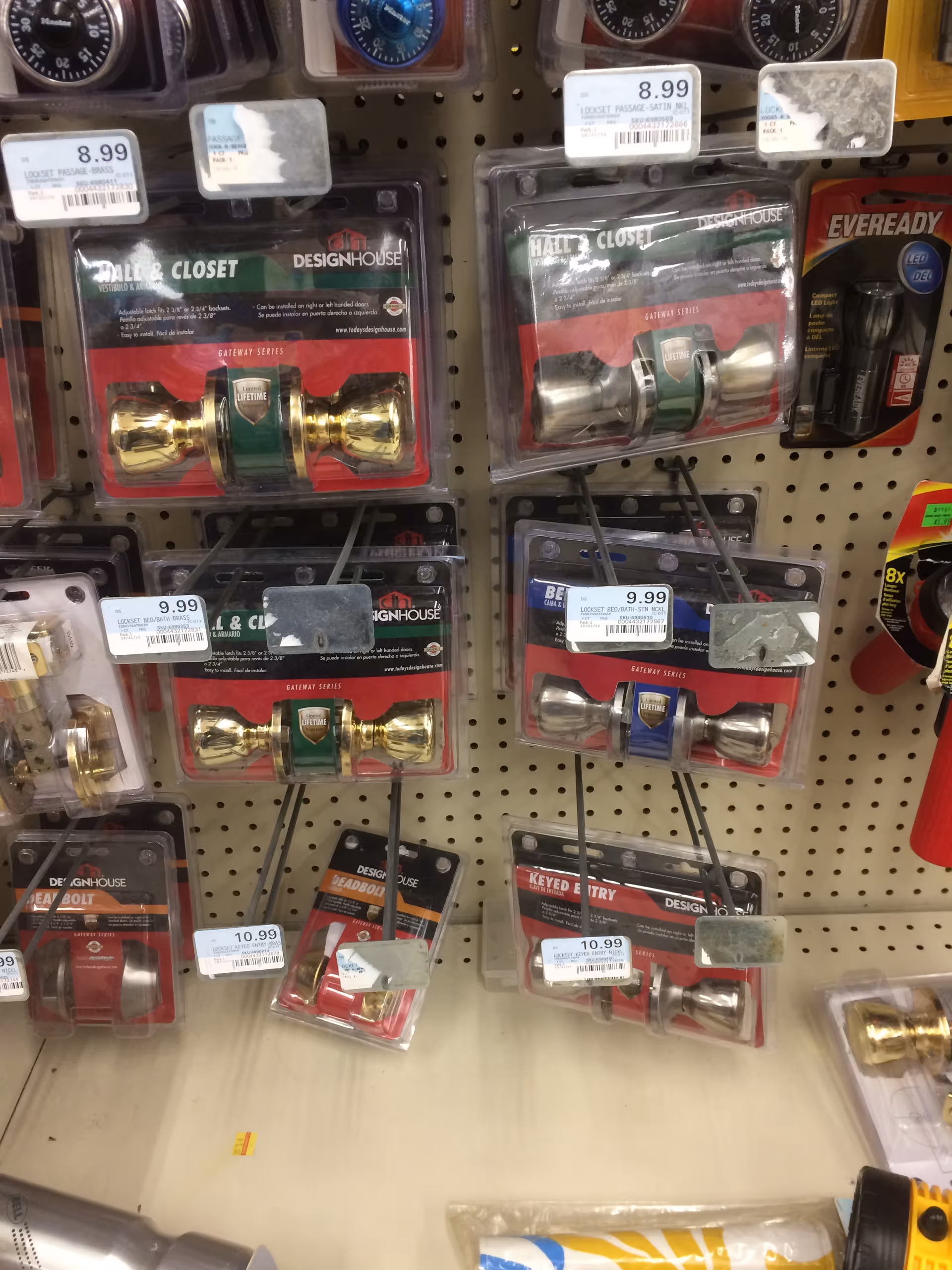 Assorted door hardware in blister packs displayed on a pegboard rack inside a store.