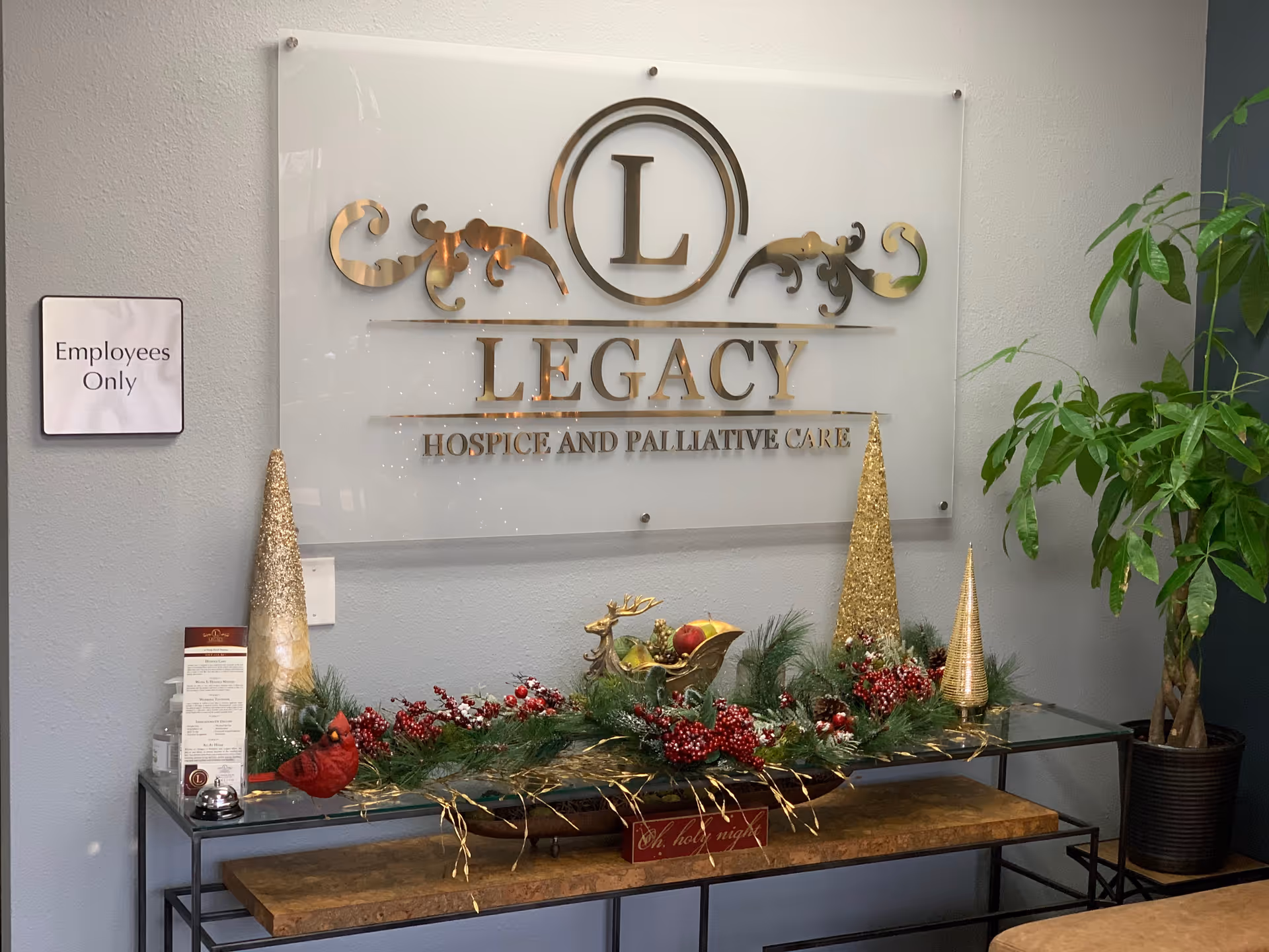 Interior lobby with Legacy Hospice sign, holiday garland, and an 'Employees Only' sign.