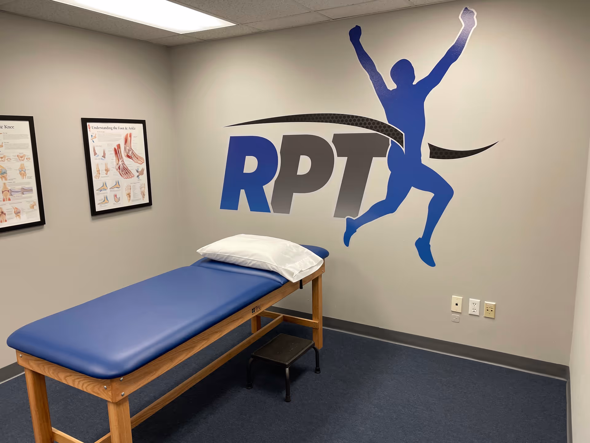 Treatment room with a blue therapy table and Rutherford Physical Therapy logo on the wall