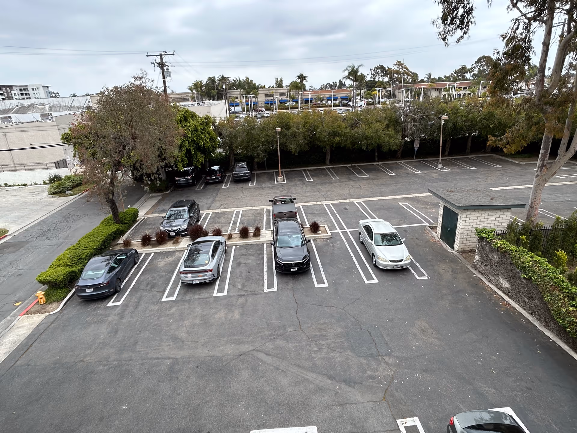 Overhead view of a parking lot with several cars and surrounding trees