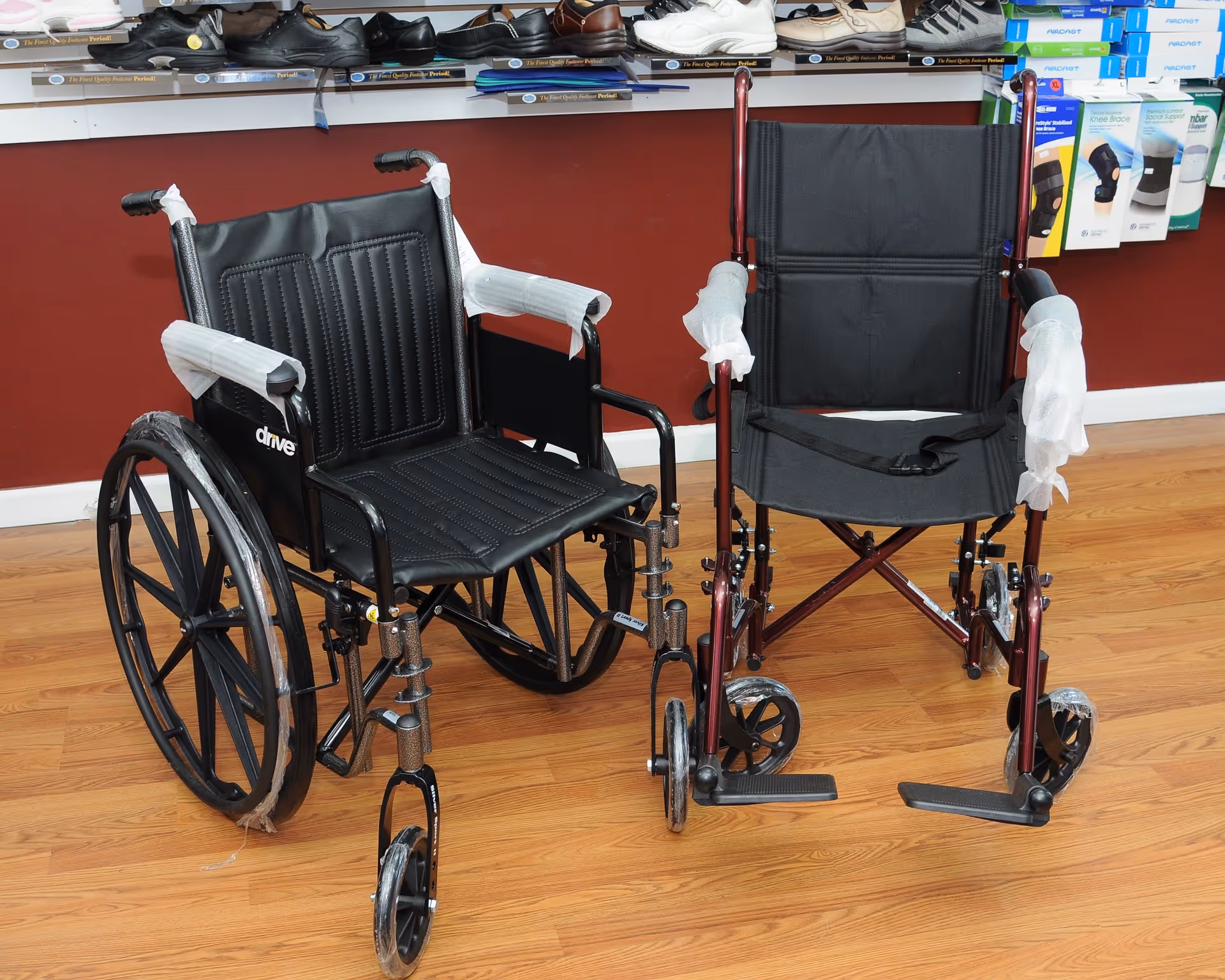 Two wheelchairs sit side by side on a wood floor inside a medical supply shop.