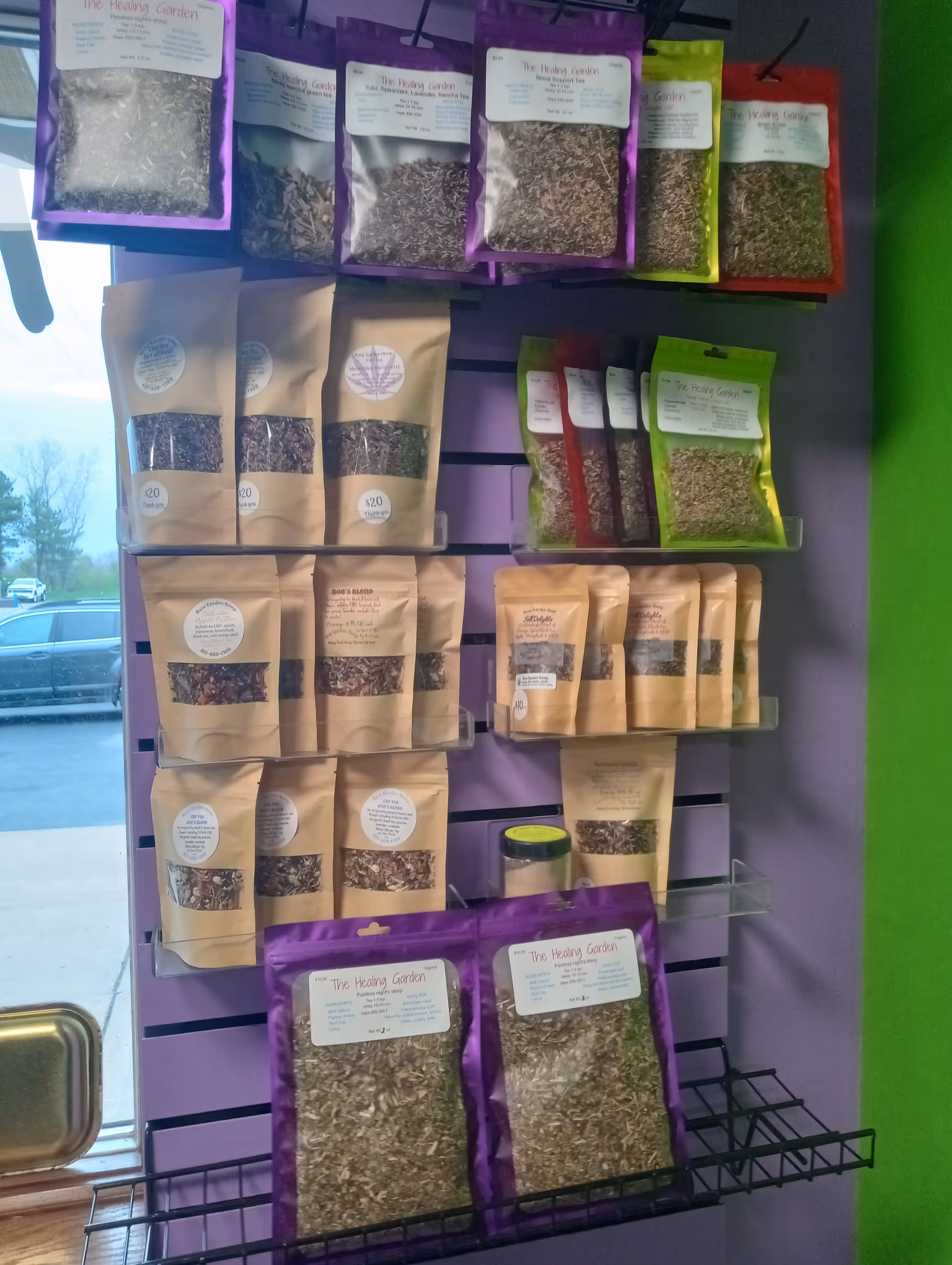 Interior wall with purple shelving displaying assorted The Healing Garden herb packets.