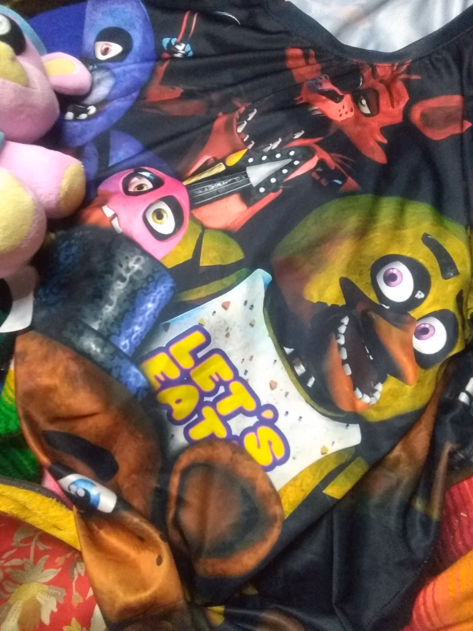 Colorful cartoon blanket with stuffed animals on a bed in a cozy bedroom.