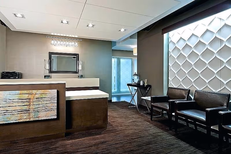 Modern reception desk with marble counter, seating area, and decorative textured wall.