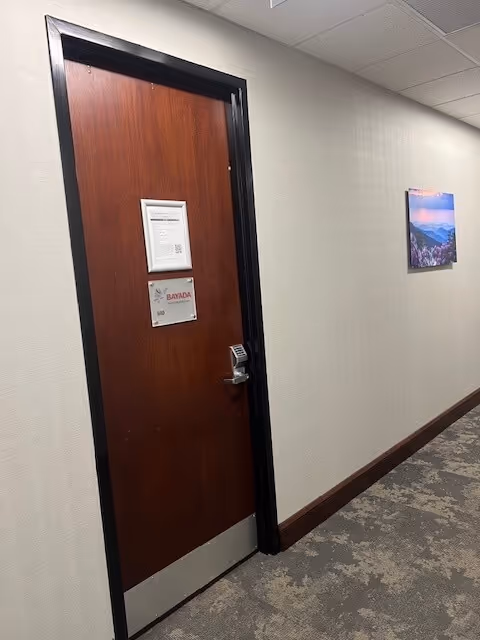 Interior hallway with a wooden door and wall art along beige walls.