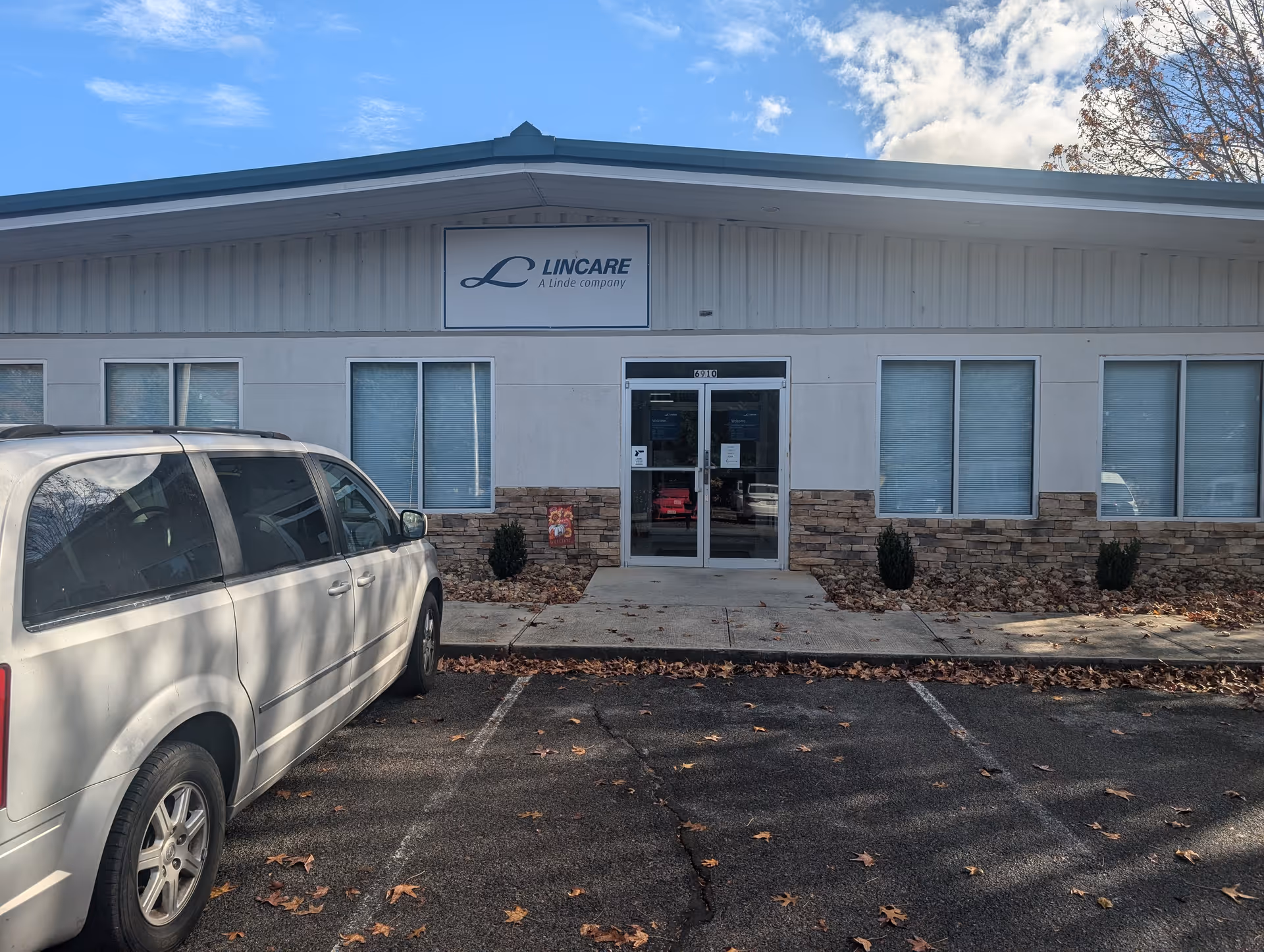 Front of LINCARE facility with sign, glass doors, and a parked white minivan.