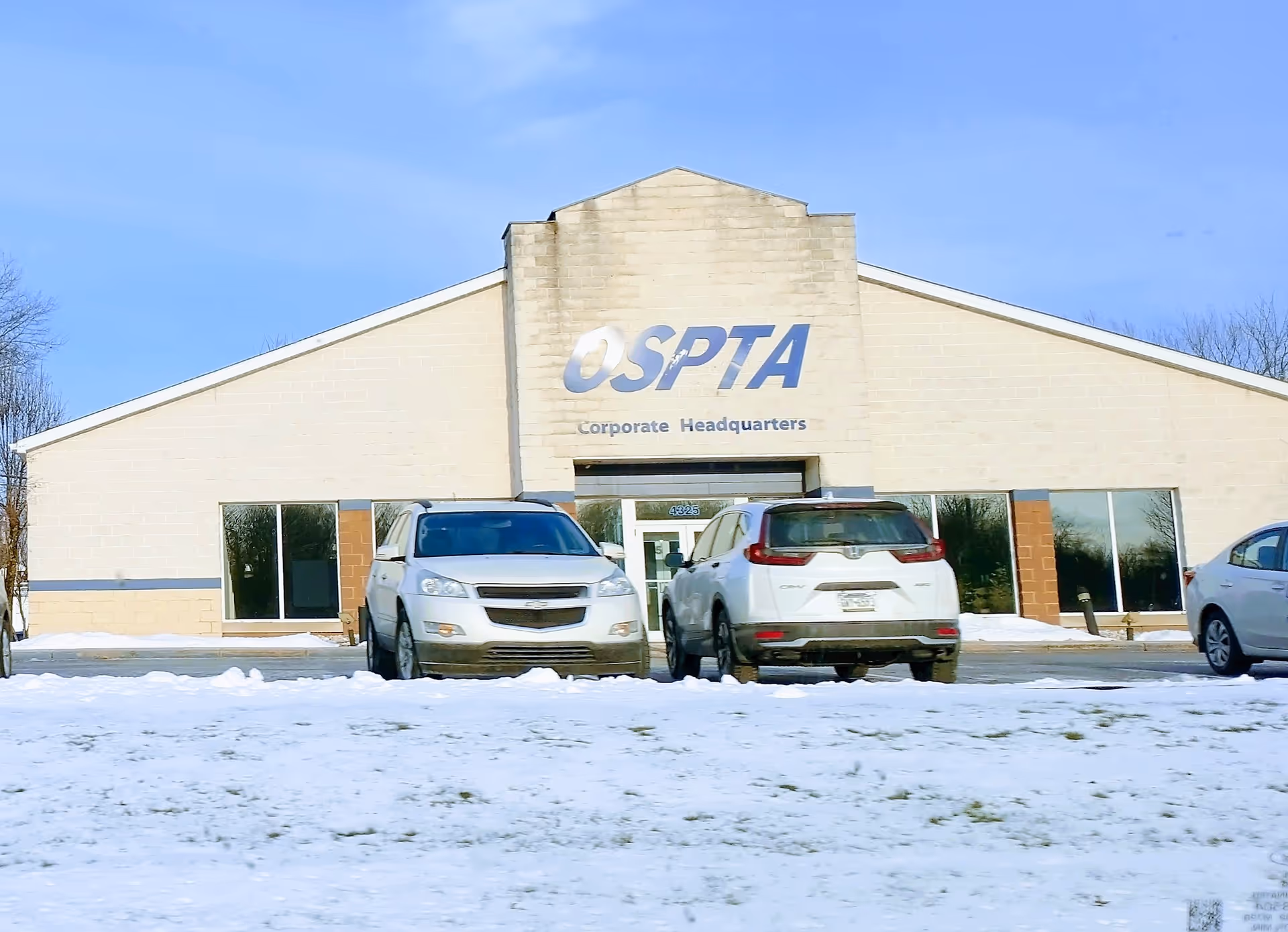 Front view of Ospta At Home facility with parked cars in snow.