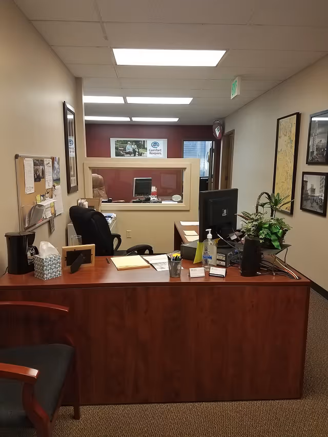 Reception desk inside a Comfort Keepers Home Care office with computer and plants.