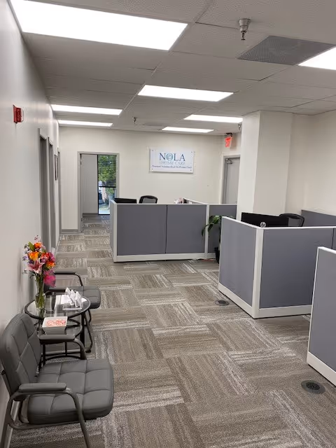 Reception area with cubicles, chairs, flowers, and a NOLA Home Care sign.