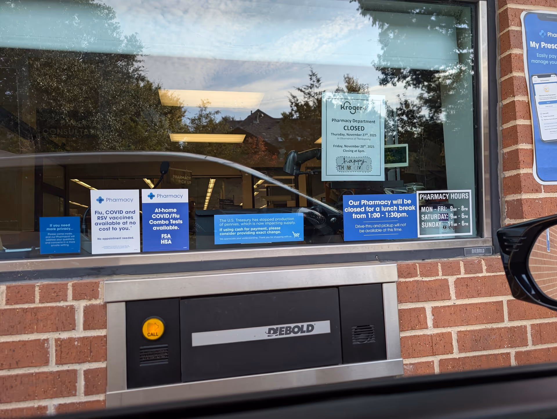 Kroger Pharmacy window with blue notices on a brick building, car visible outside