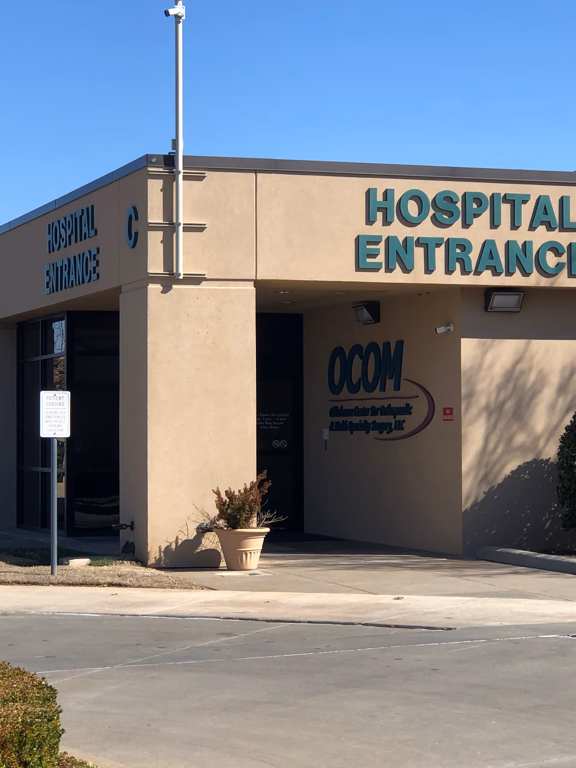 Beige hospital exterior with large HOSPITAL ENTRANCE sign and covered entry.