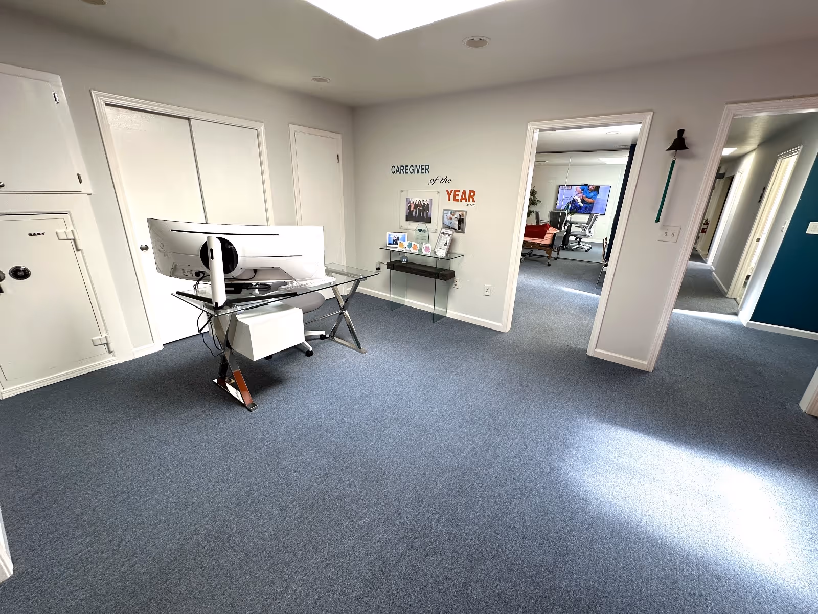 Office workspace with computer desk and hallway in a senior living facility.