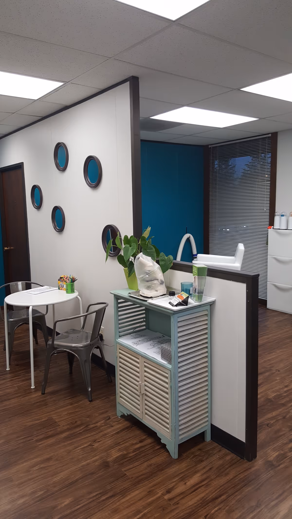 Interior of a senior facility lobby with a round table, chairs, plant, and reception counter.