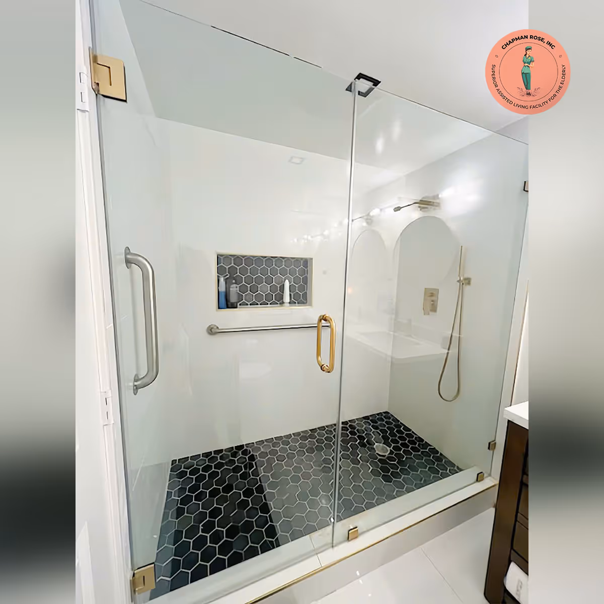 Glass-walled shower with black hex tile floor in a bright bathroom.