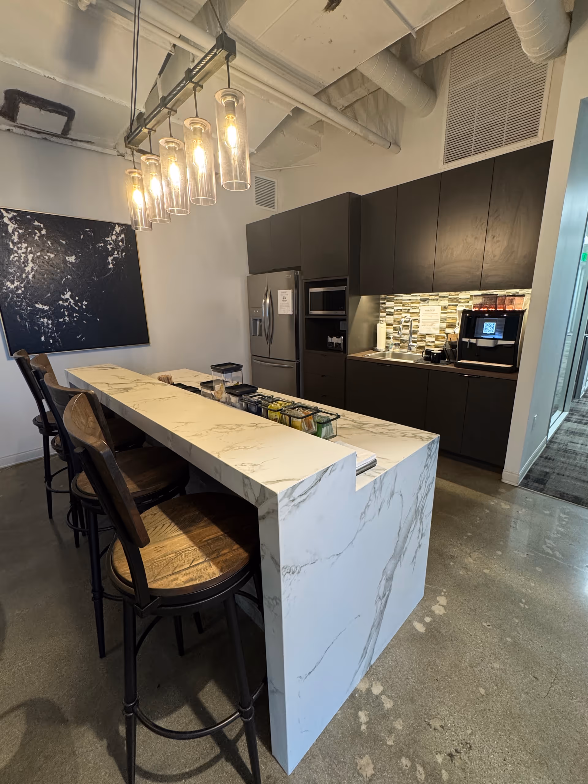 Modern marble island with bar stools and pendant lights in a sleek kitchen.