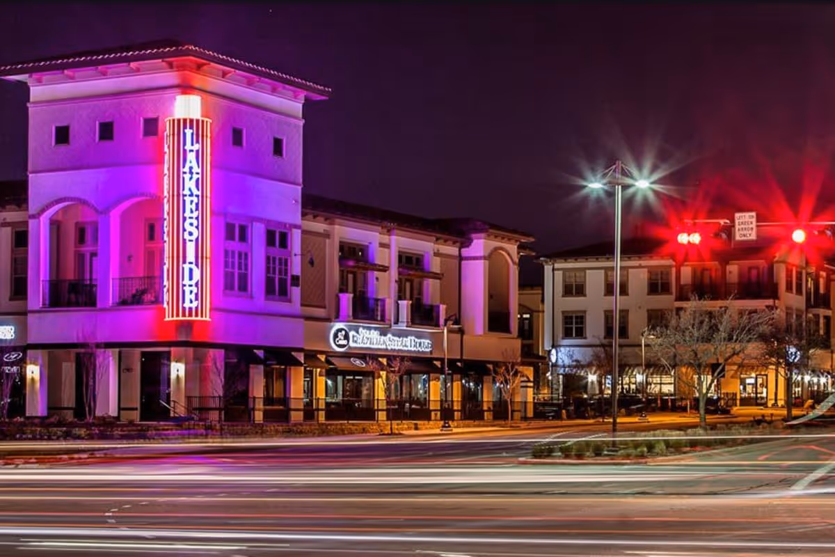 Nighttime exterior of a lit building with purple neon signage along a busy street.