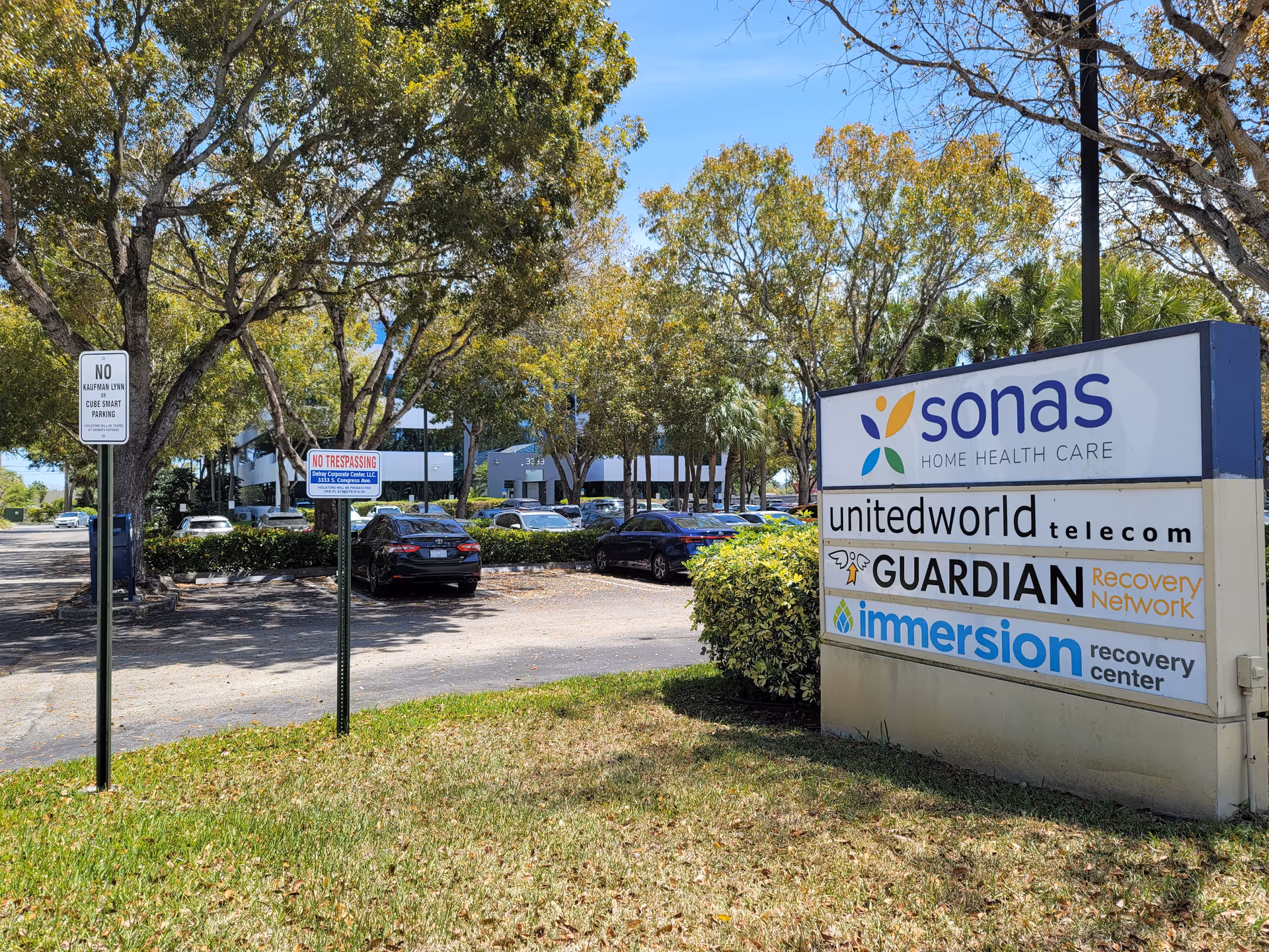 Outdoor scene with parking lot, trees, and a large signboard for care services
