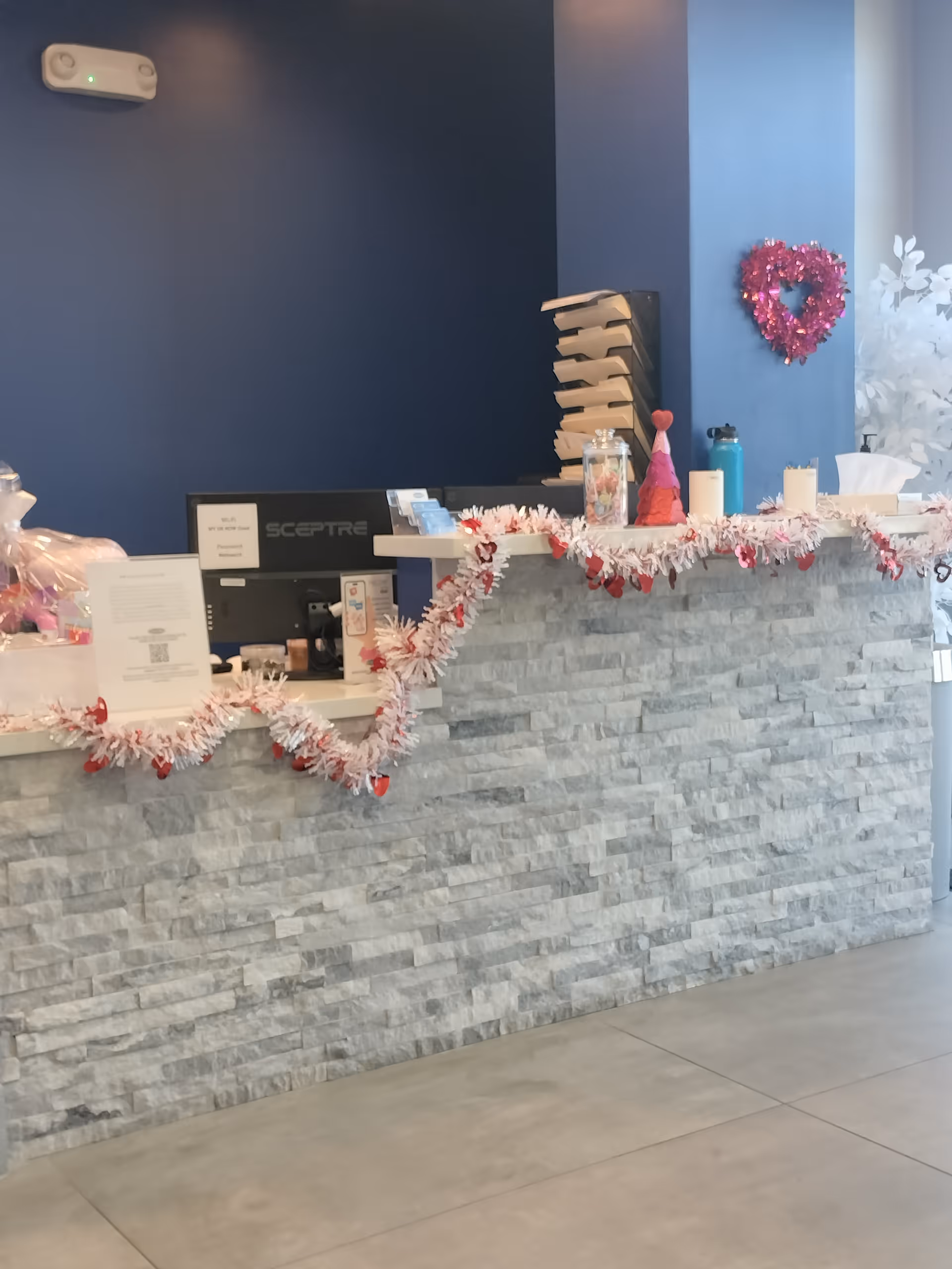 Reception desk with a stone front and Christmas garlands in a blue-walled senior living facility lobby.