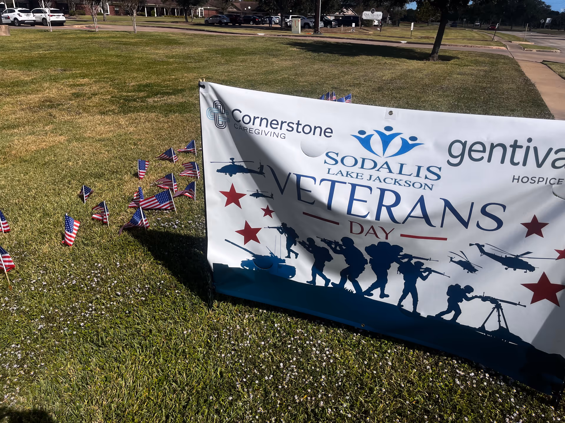 Outdoor lawn with a Cornerstone Caregiving banner and small American flags.