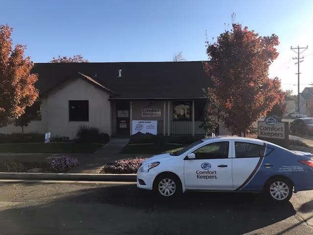 Front exterior of Comfort Keepers Home Care building with a branded car parked outside.