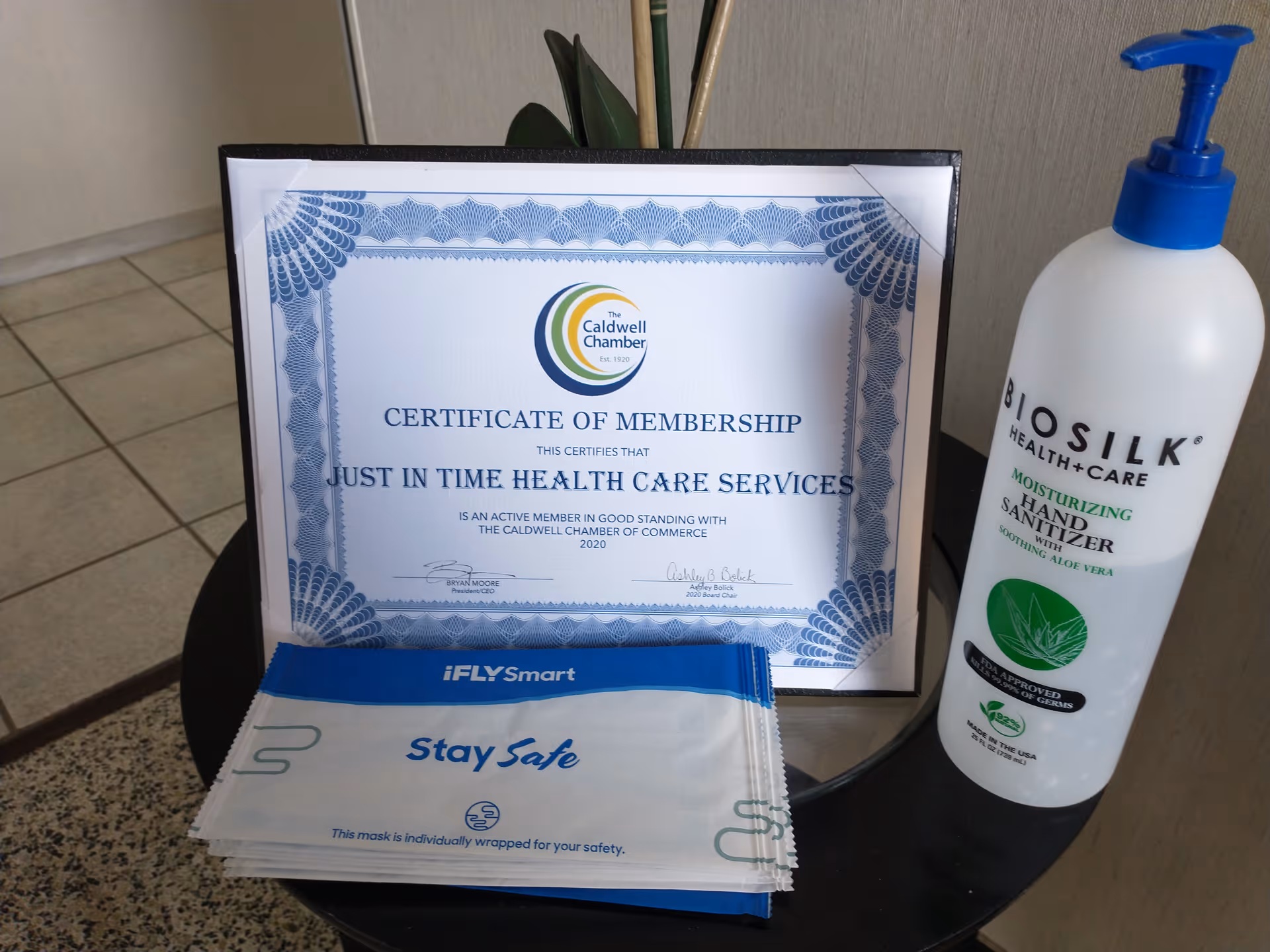 Certificate of membership for Just in Time Health Care Services on a desk beside hand sanitizer.