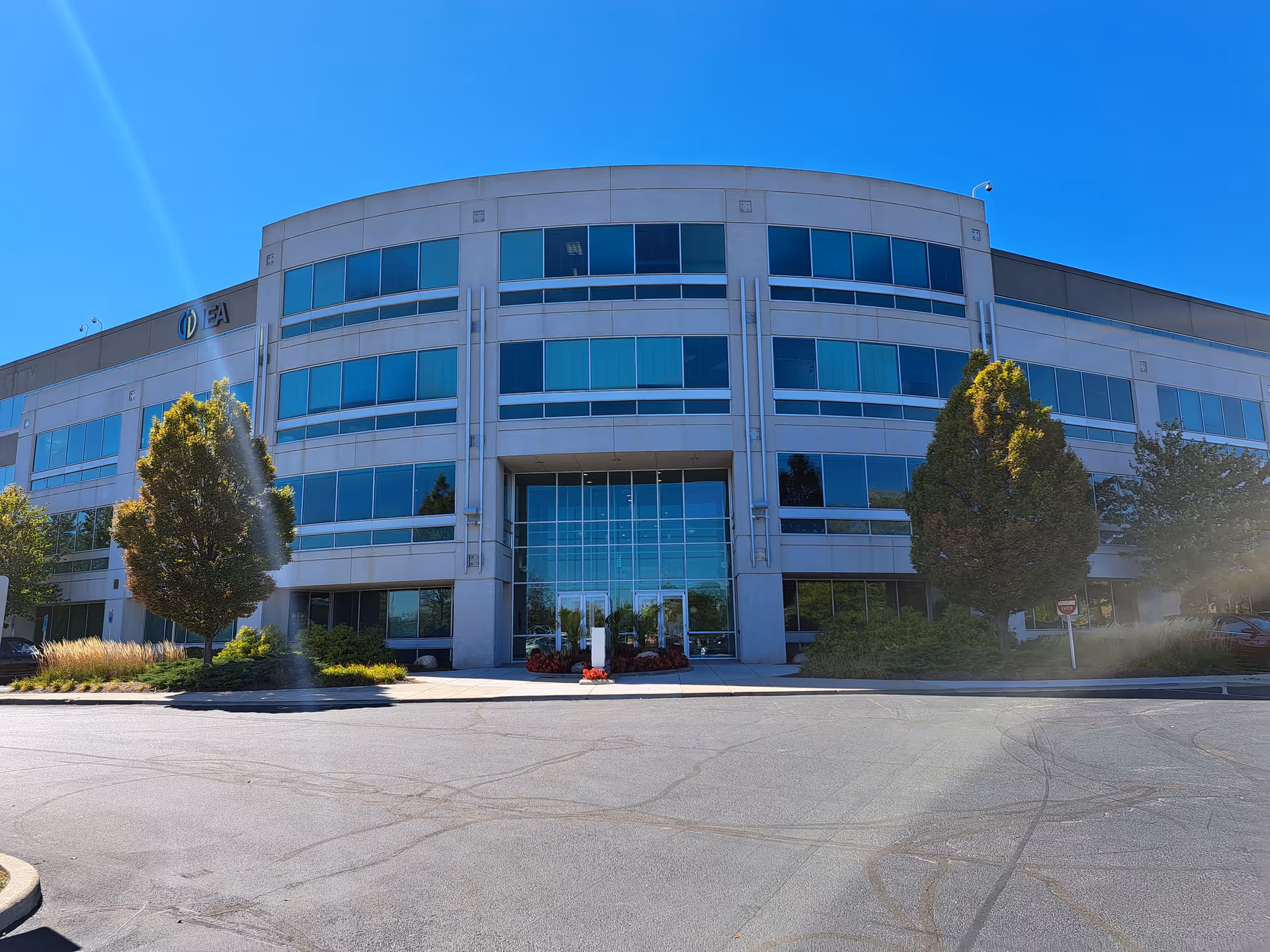 Modern multi-story building with glass entrance and landscaping under blue sky
