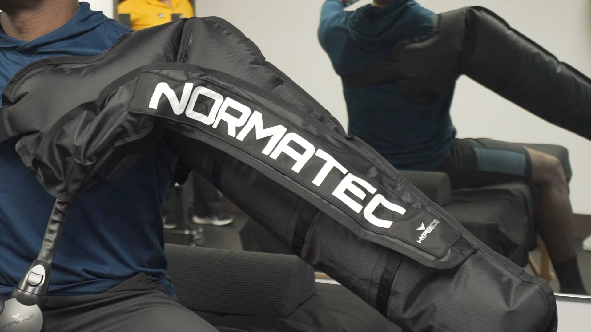 Close-up of a person wearing a NormaTec compression sleeve during a therapy session.
