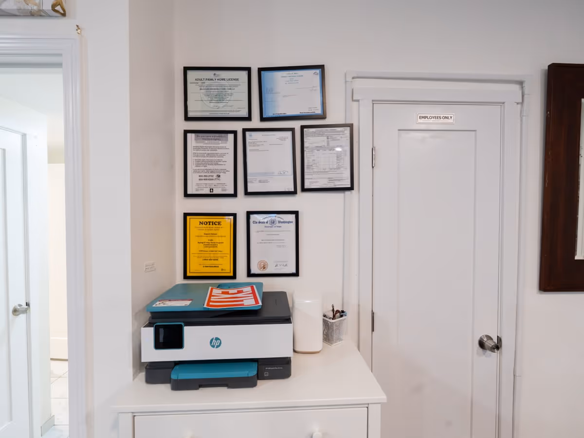 Printer on a white cabinet beside framed certificates and an Employees Only door.