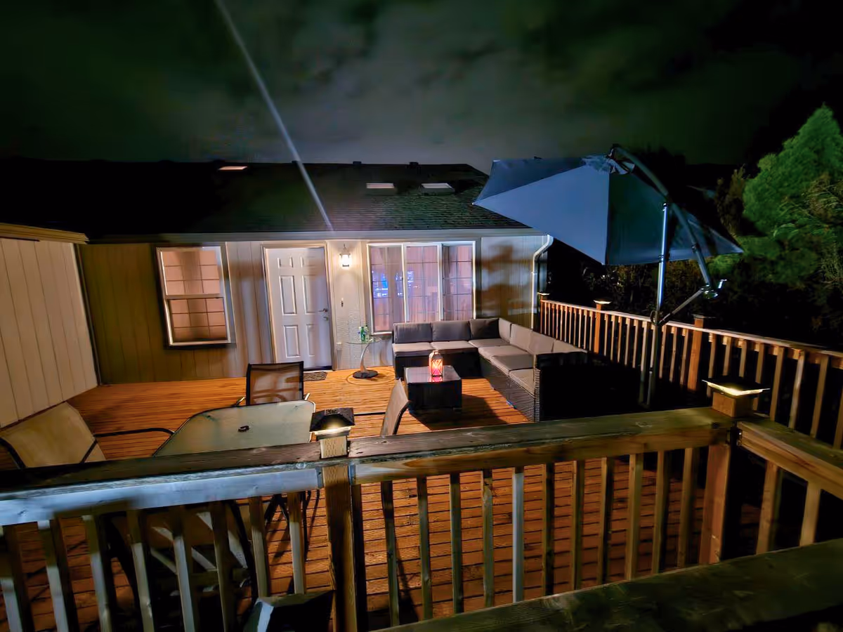 Night view of an illuminated outdoor deck with seating and umbrella.