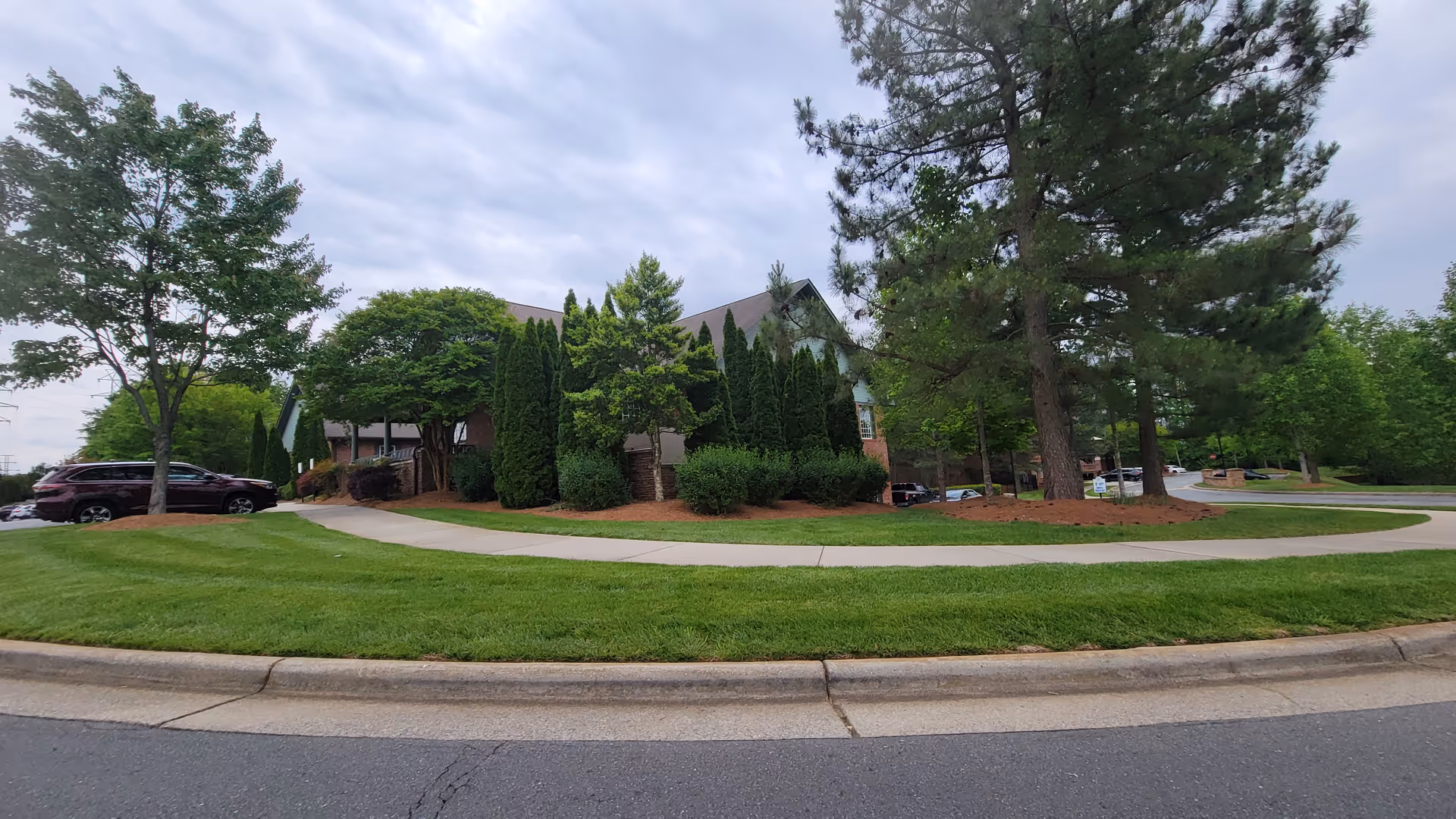 Exterior view of Trellis Supportive Care facility with curved driveway and landscaped trees.