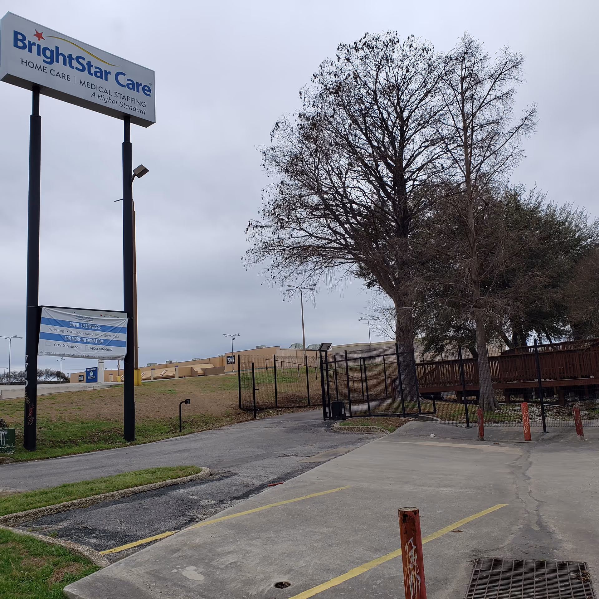 BrightStar Care exterior sign towers over a parking lot with leafless trees.