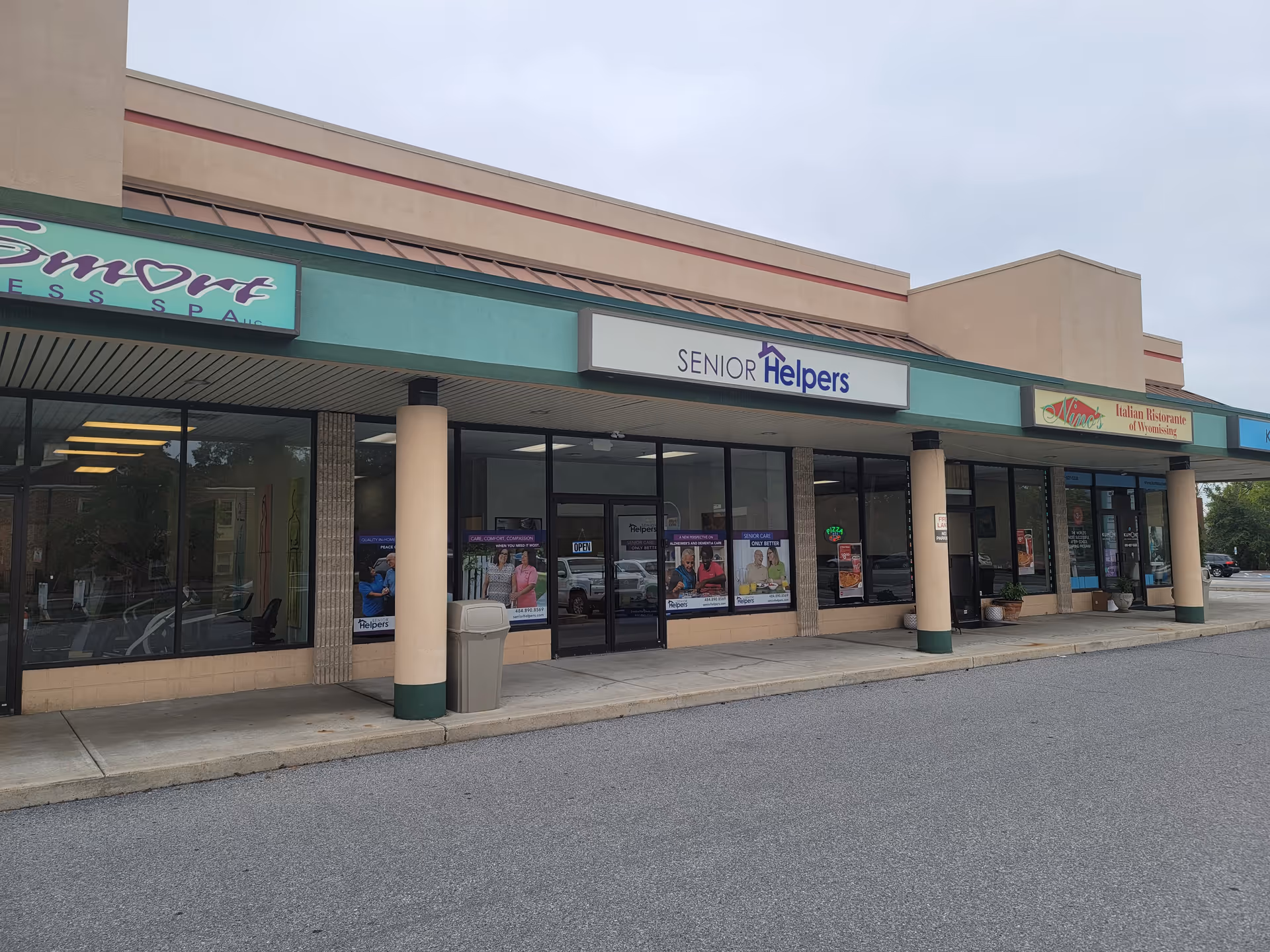 Strip mall storefronts featuring a Senior Helpers sign and neighboring shops.