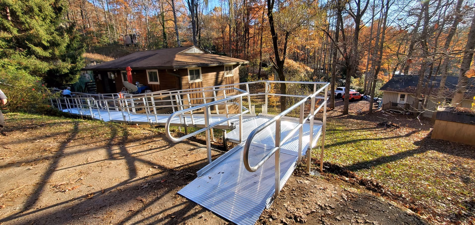 Wheelchair ramp outside a wooden cabin in a wooded area.