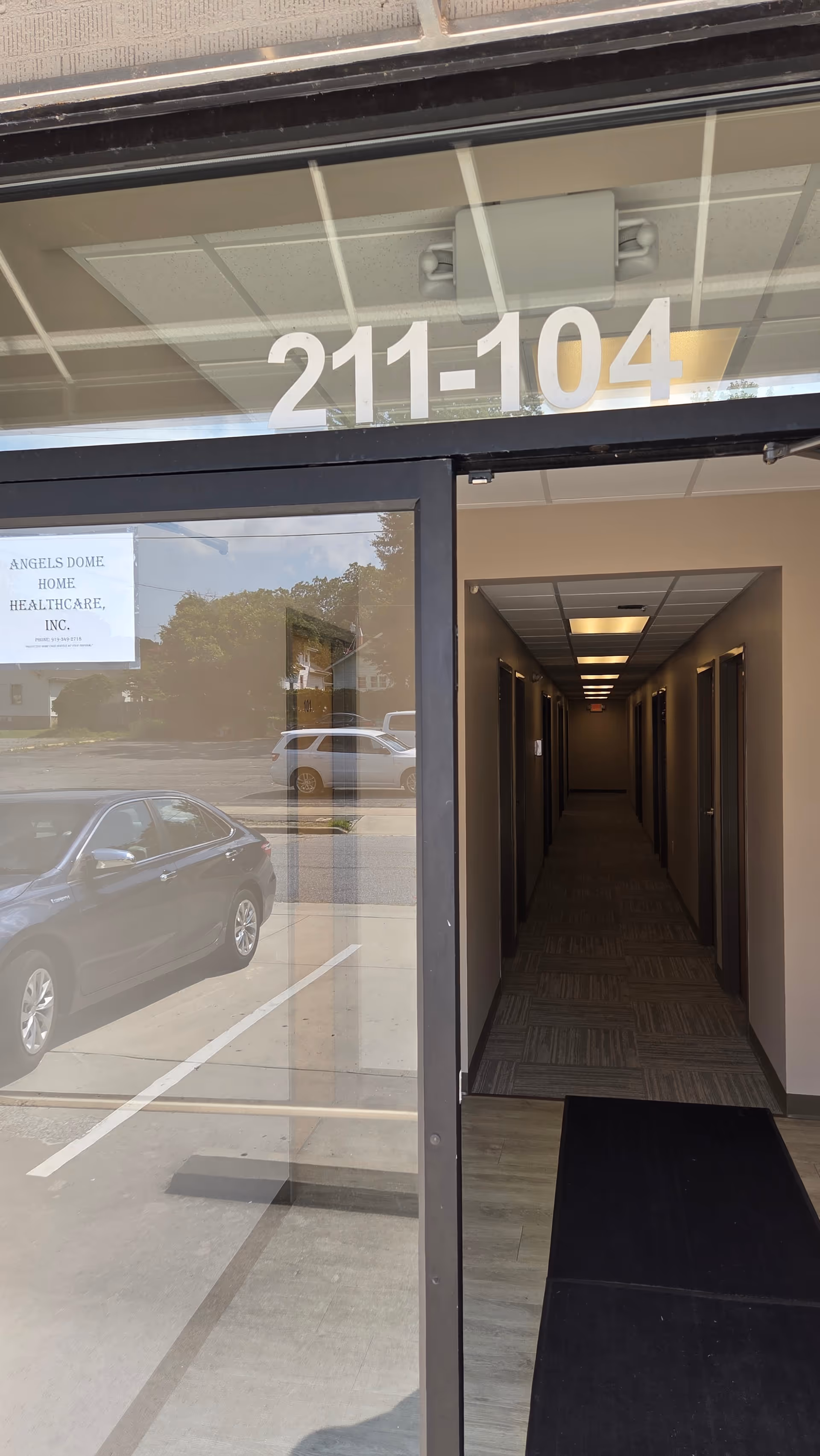 Glass entrance with unit numbers 211-104 and a long interior hallway.