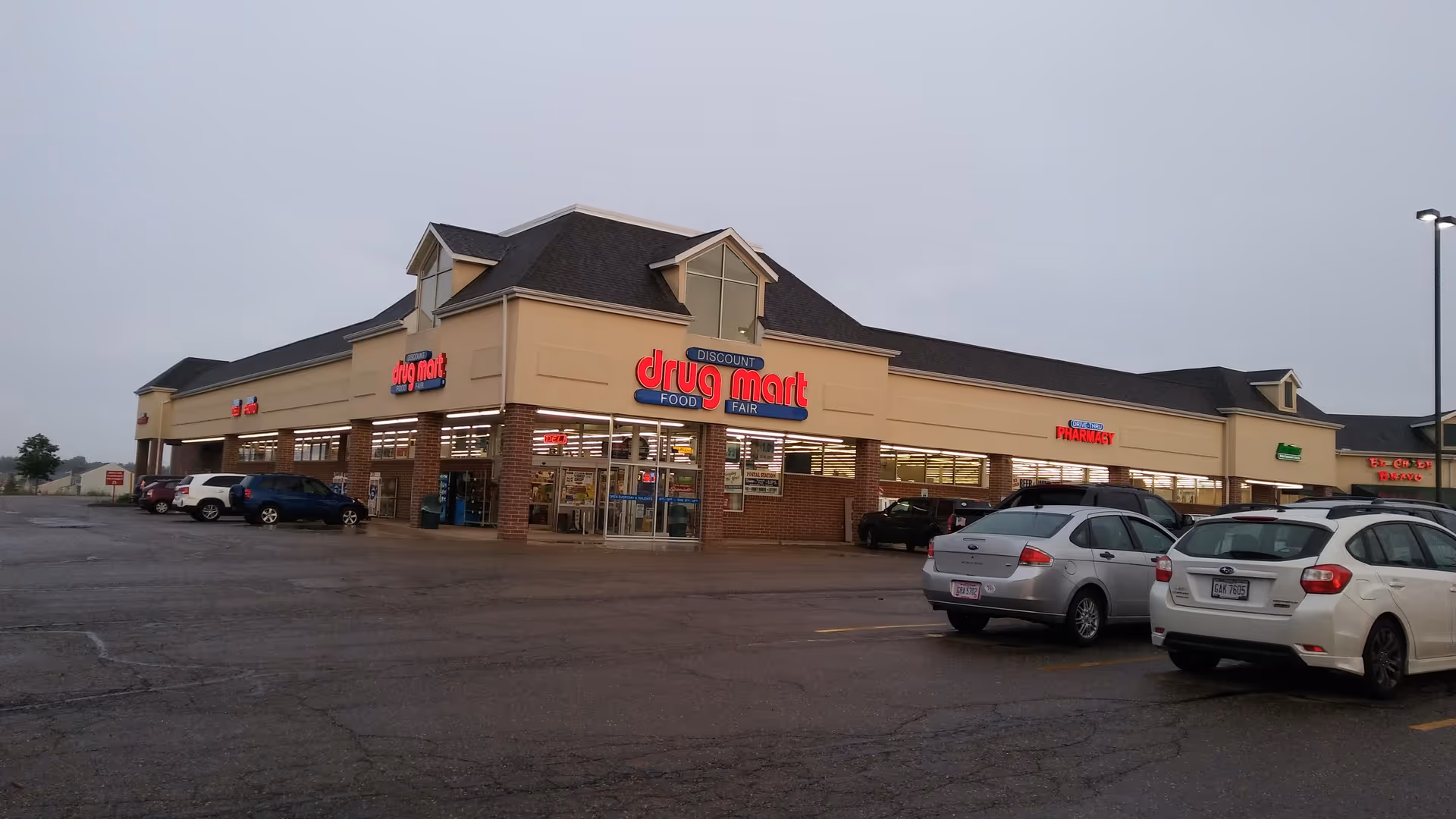 Exterior view of a Discount Drug Mart storefront with a parking lot in front.
