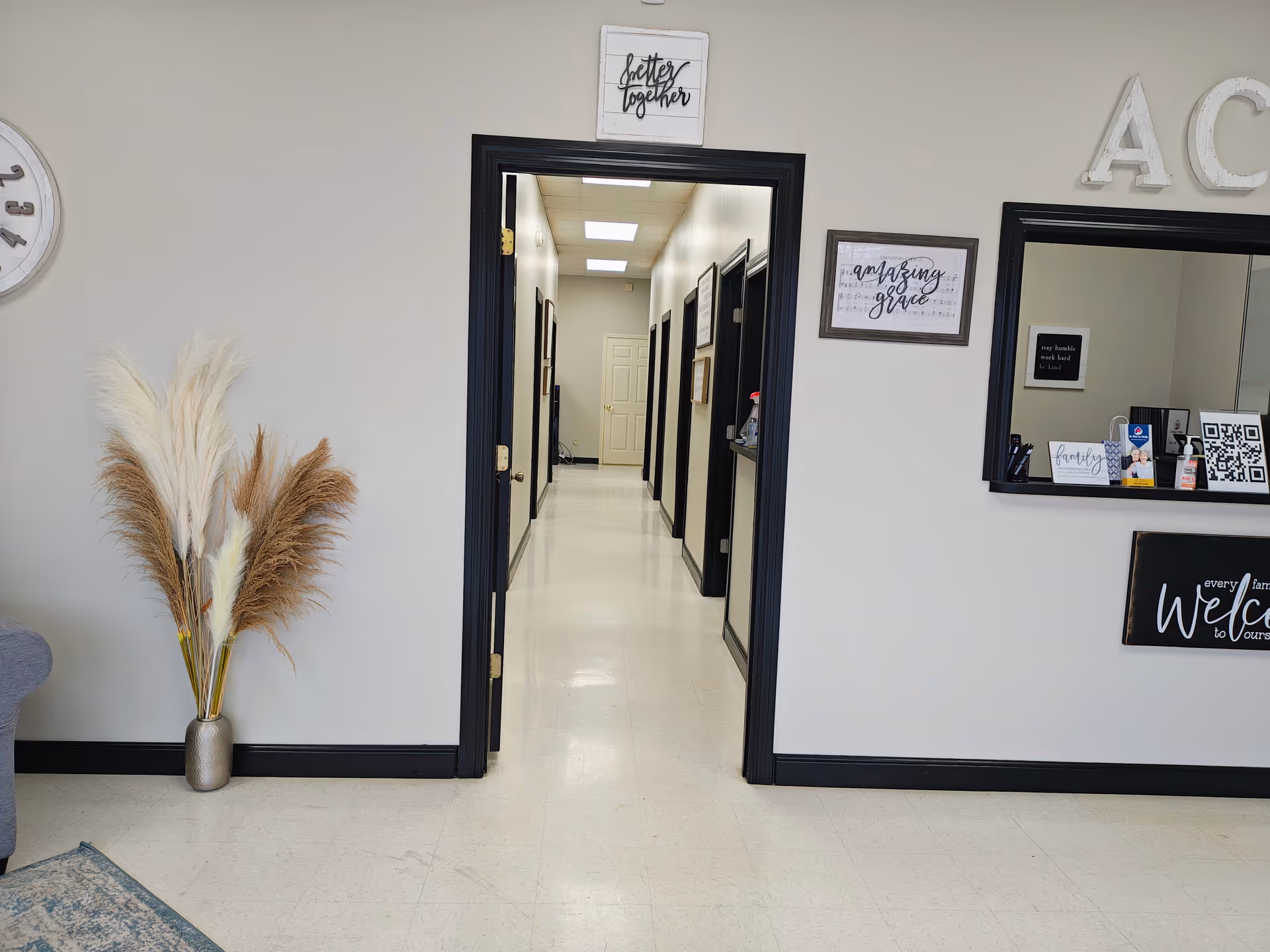 Bright hallway inside a senior living facility, with a reception window and decorative plants.