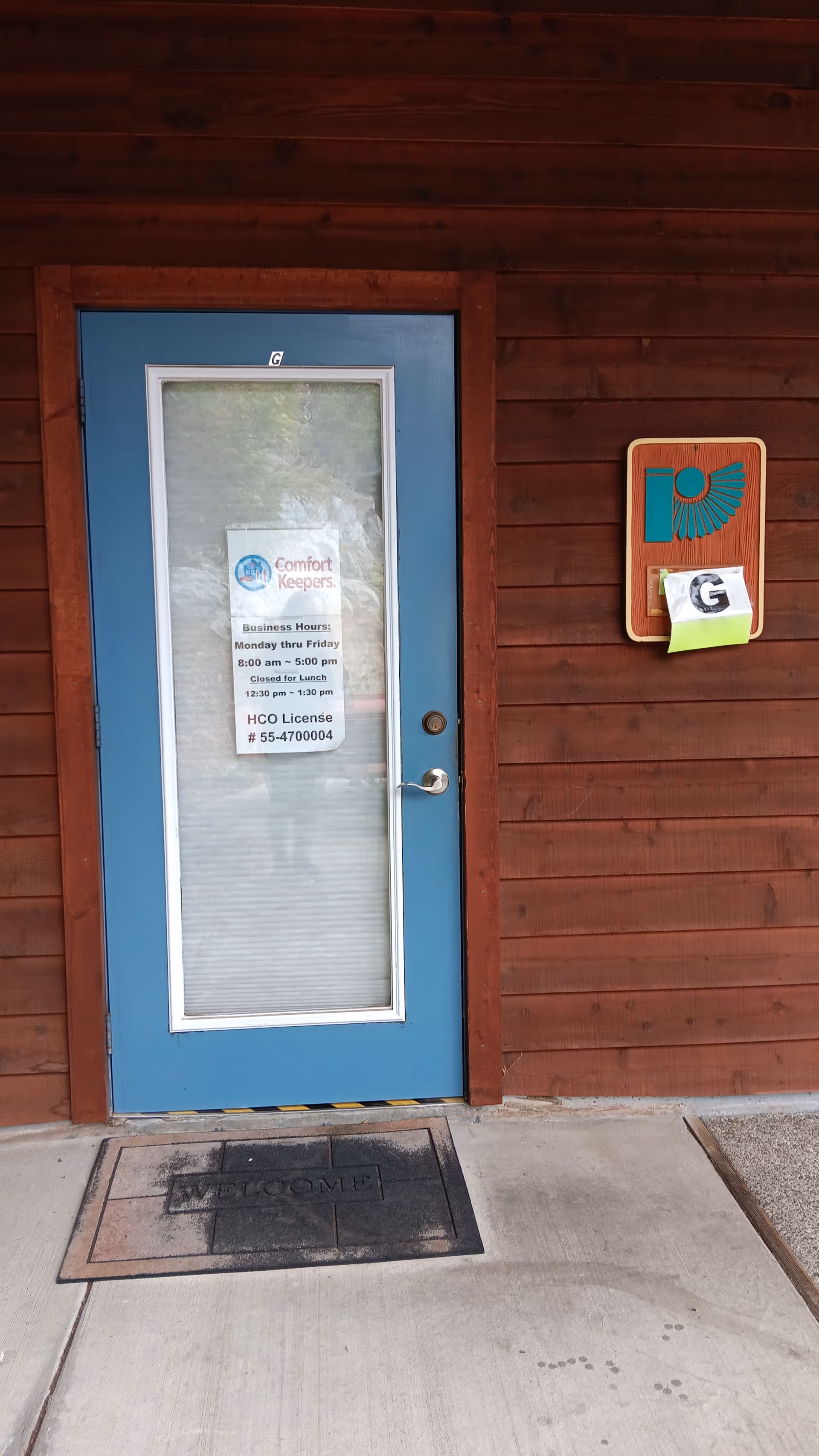 Blue front door with Comfort Keepers sign on wooden exterior wall.