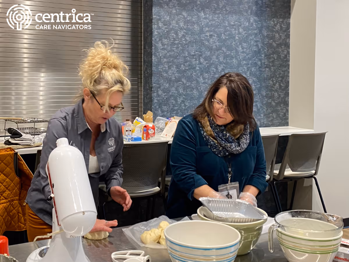 Two staff members prepare food with a mixer in a Centrica Care Navigators facility kitchen.