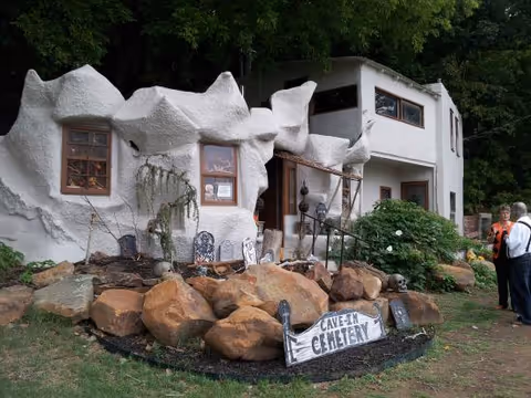 Quirky white building with rocky landscaping and two people near the entrance.