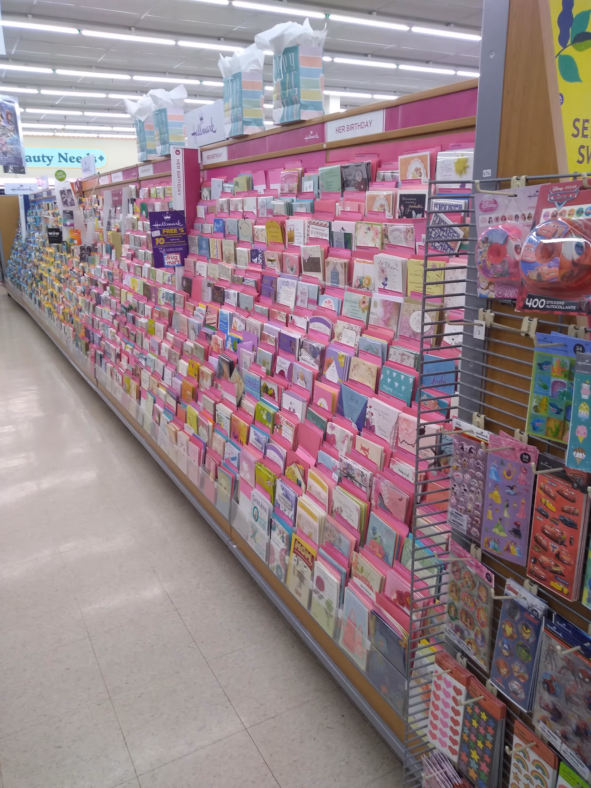 A long aisle of pink greeting cards and gifts in a discount drugstore.