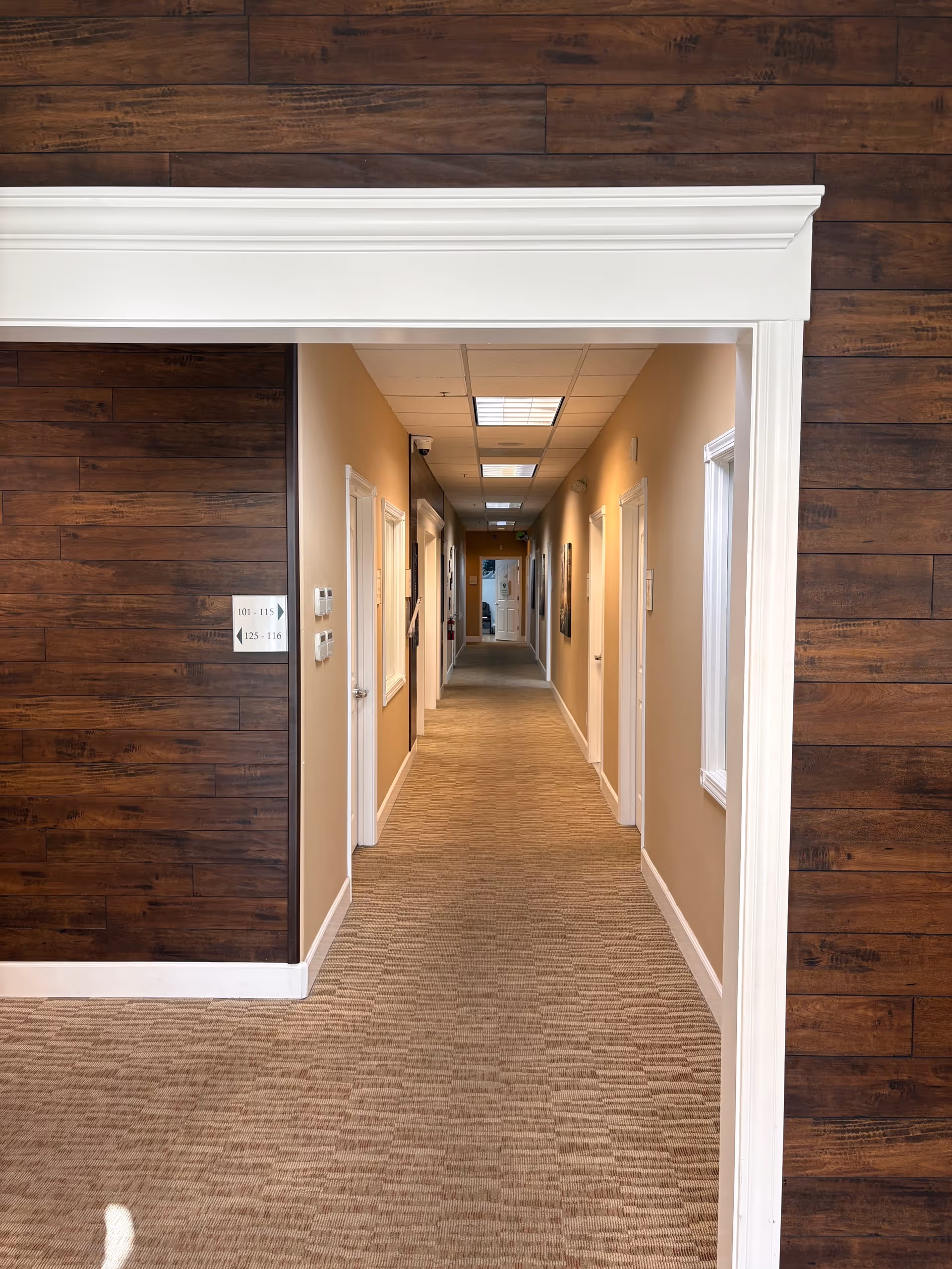 Interior hallway at Amada Senior Care facility with beige walls and closed doors.