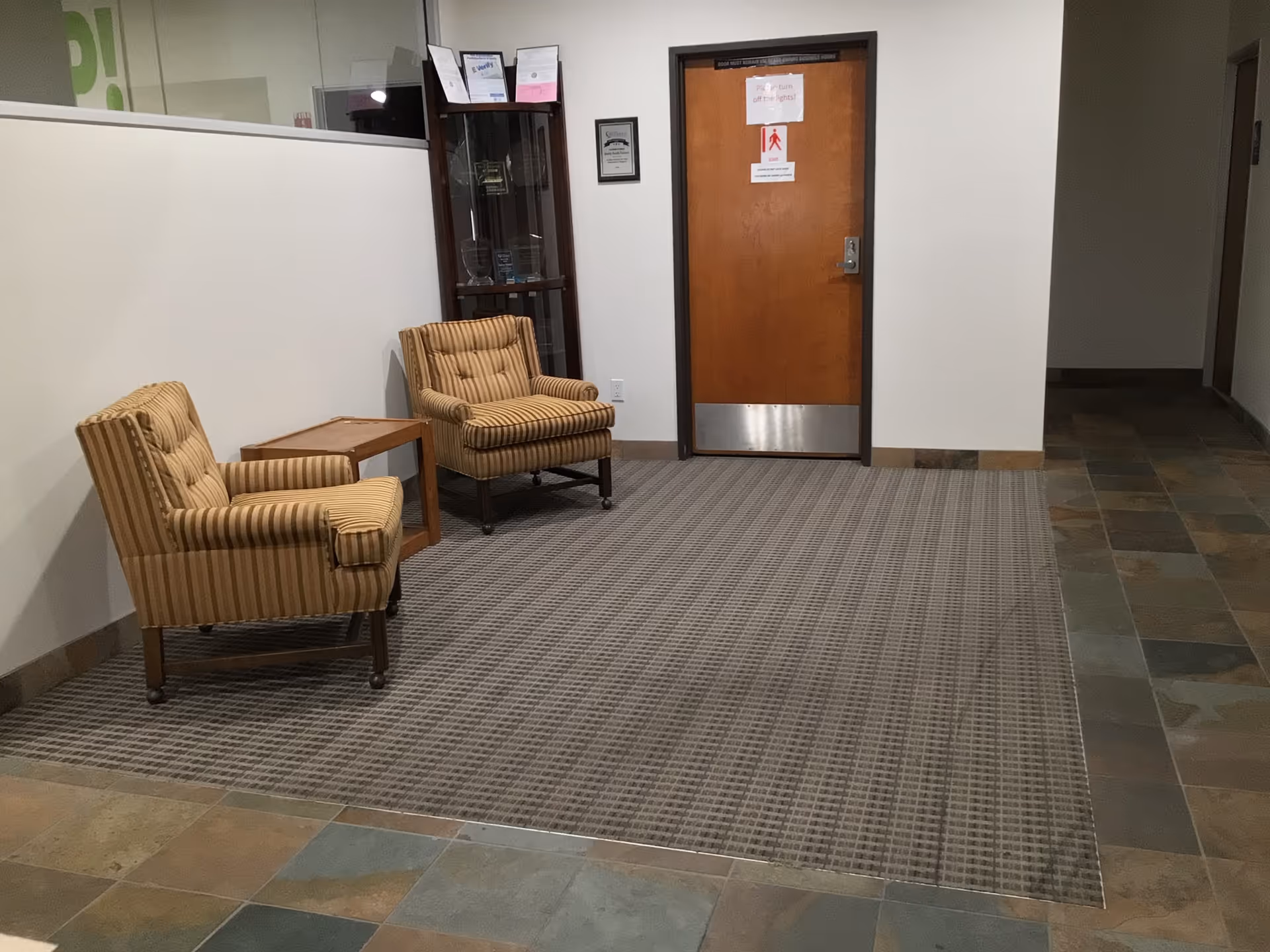 Two striped armchairs with a small table in a neutral lobby area.