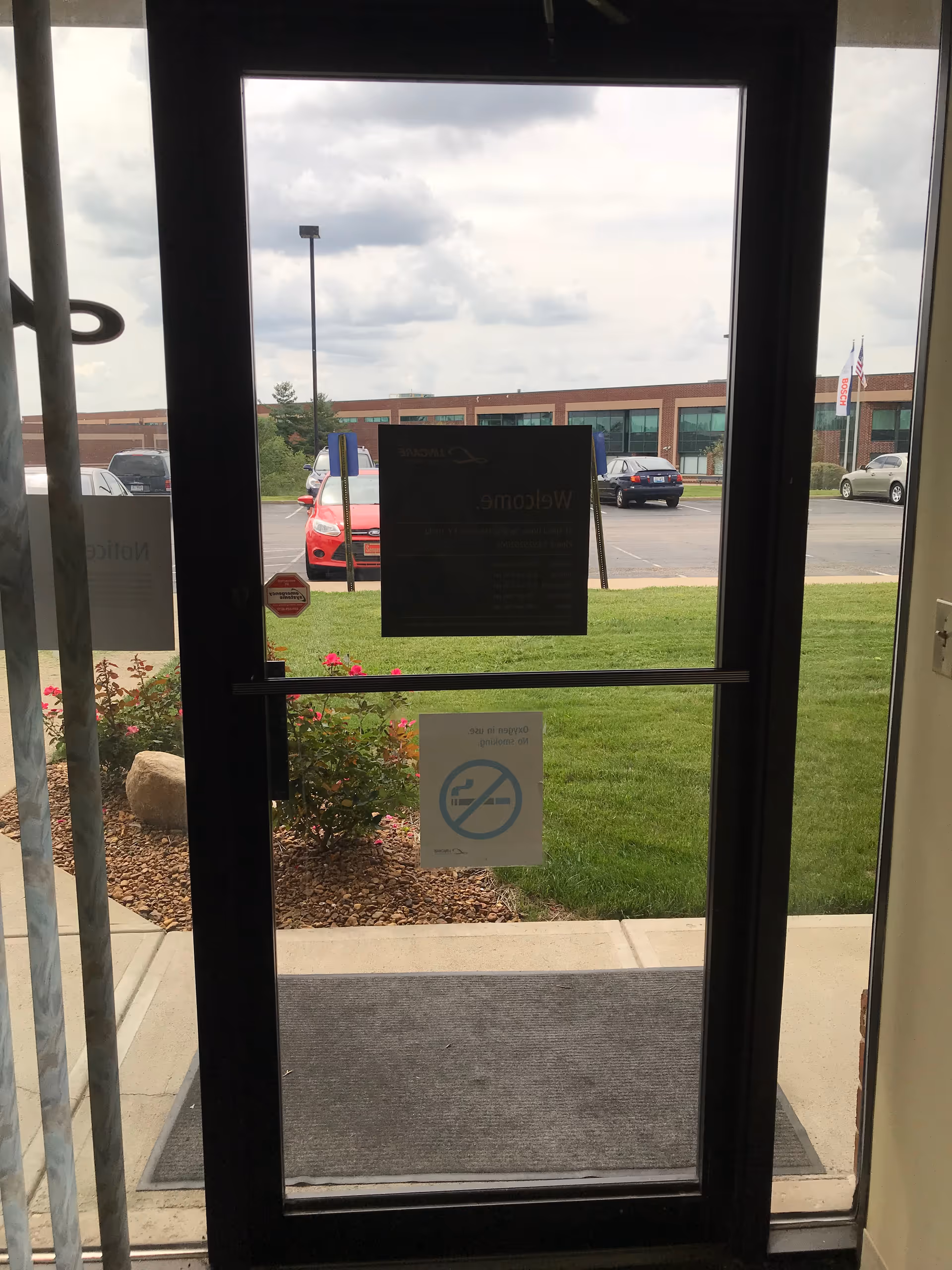 Interior entry with glass door opening to a parking lot and building outside.