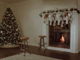 Cozy senior living room with a Christmas tree, fireplace, stockings, and stools.