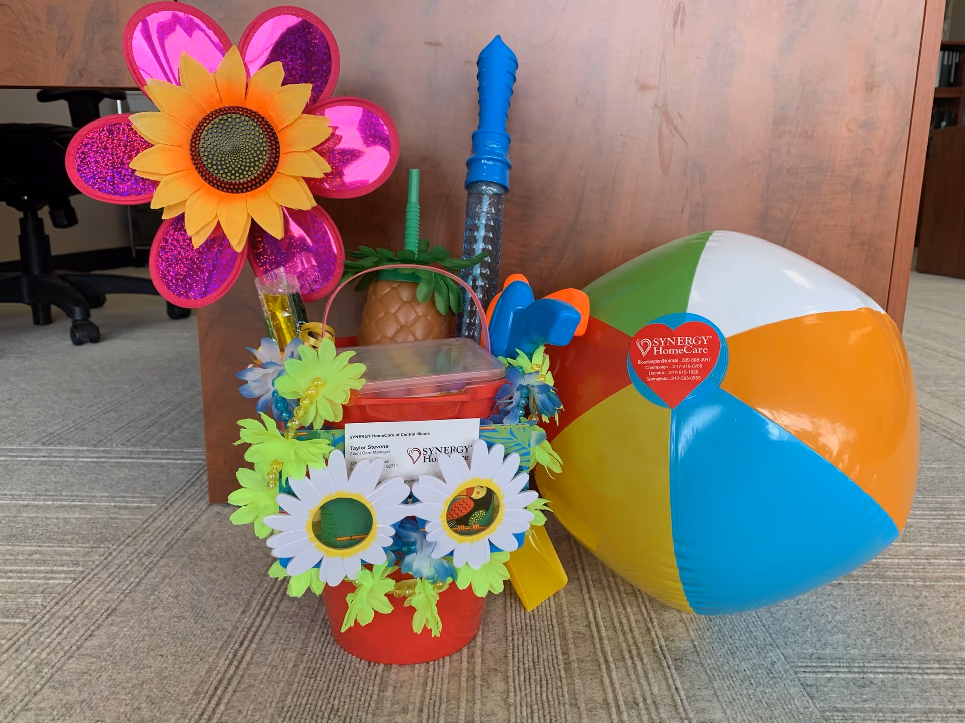 Colorful office decorations and a large beach ball by a cabinet.