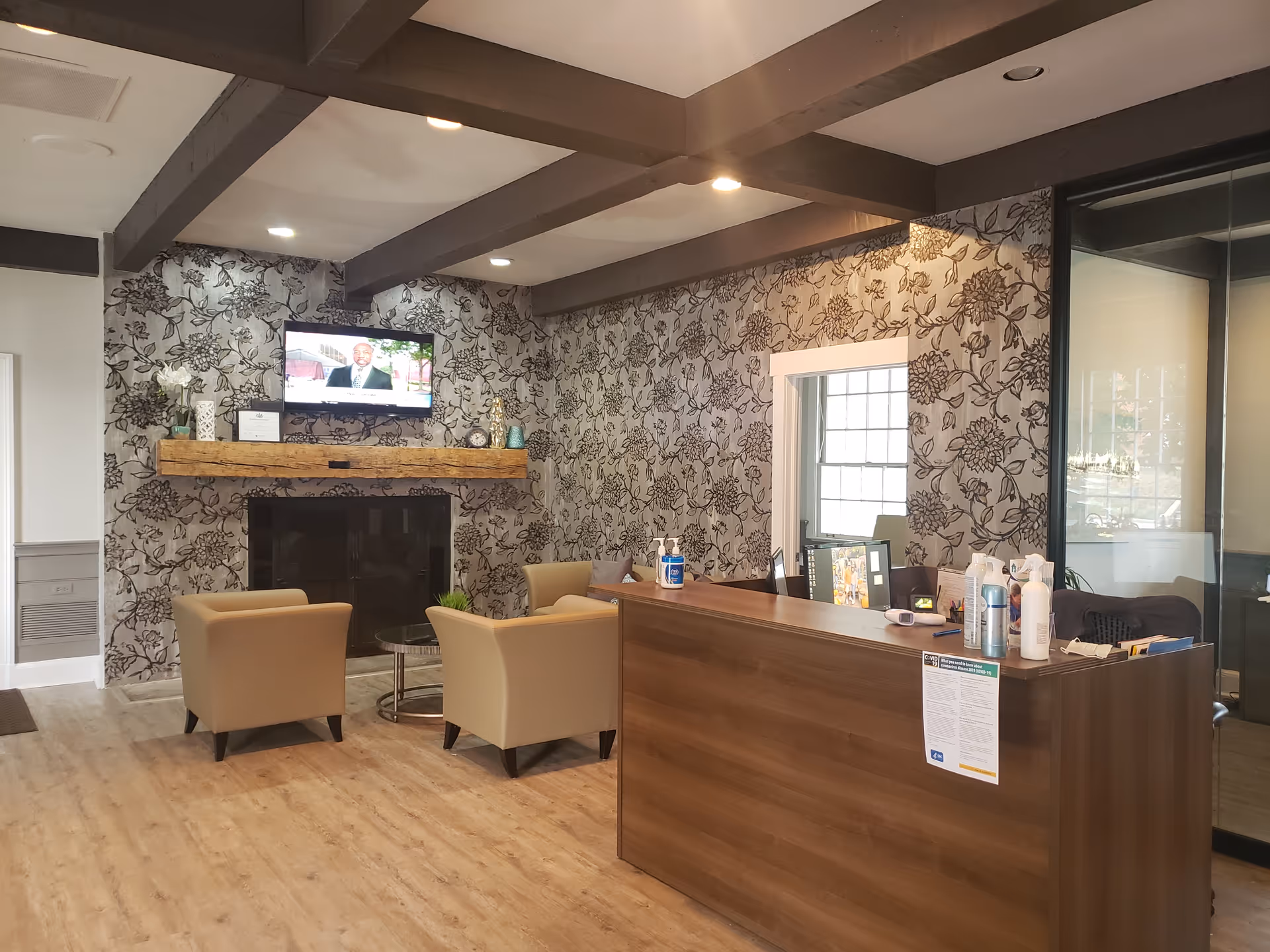 Interior reception area at Harmony Home Care with a wooden desk, fireplace, and floral wallpaper.