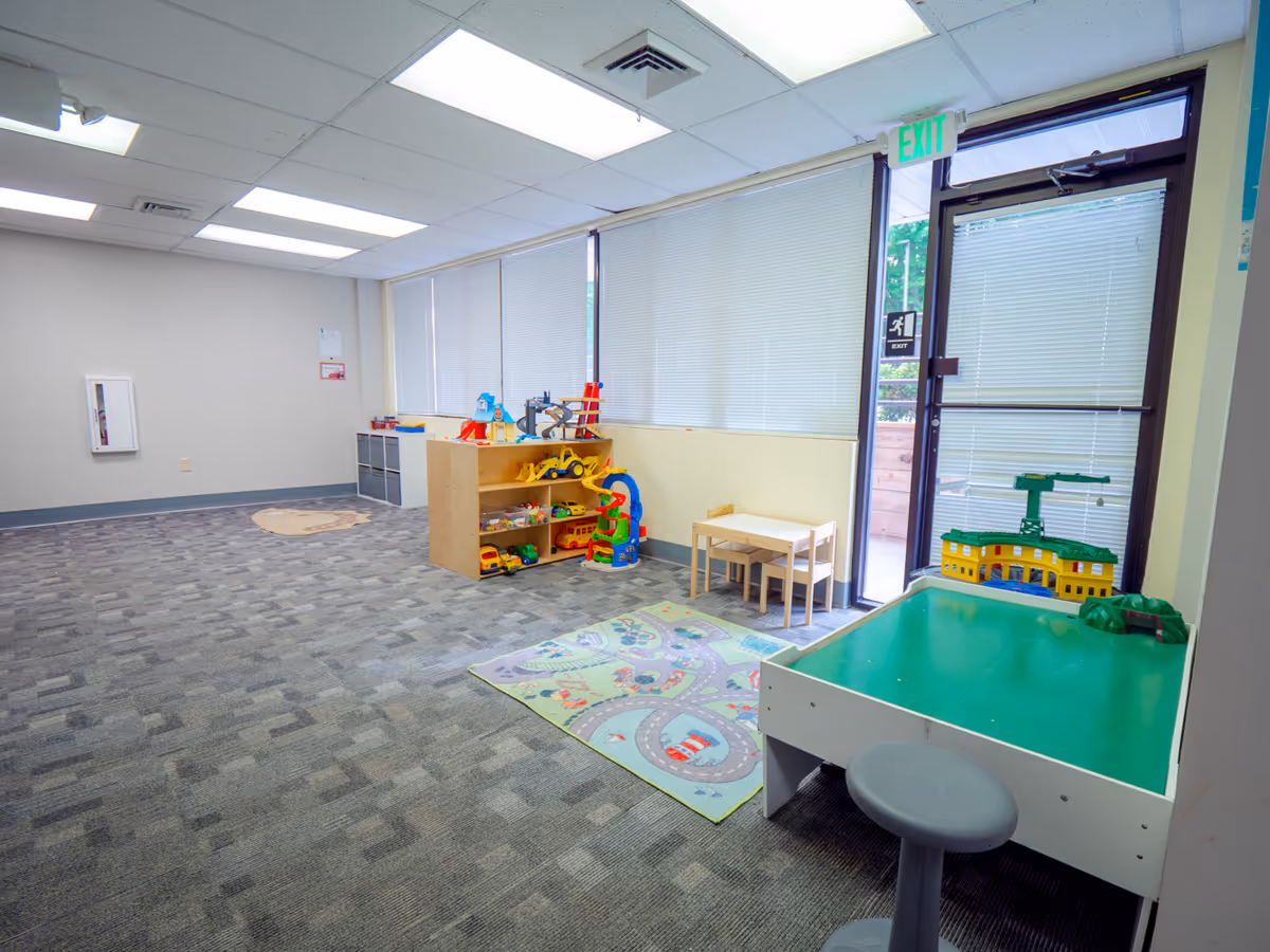 Interior play area in Trellis Services facility with toy shelves, rug, and activity table.