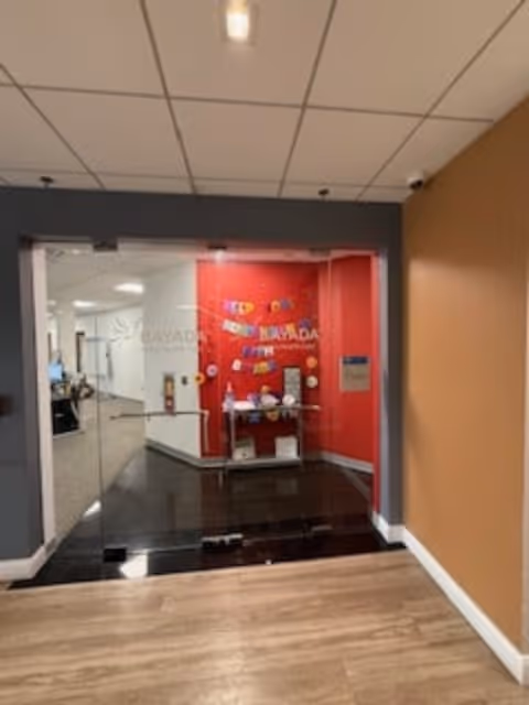 Glass doors open into a reception area with a red accent wall inside BAYADA Assistive Care.